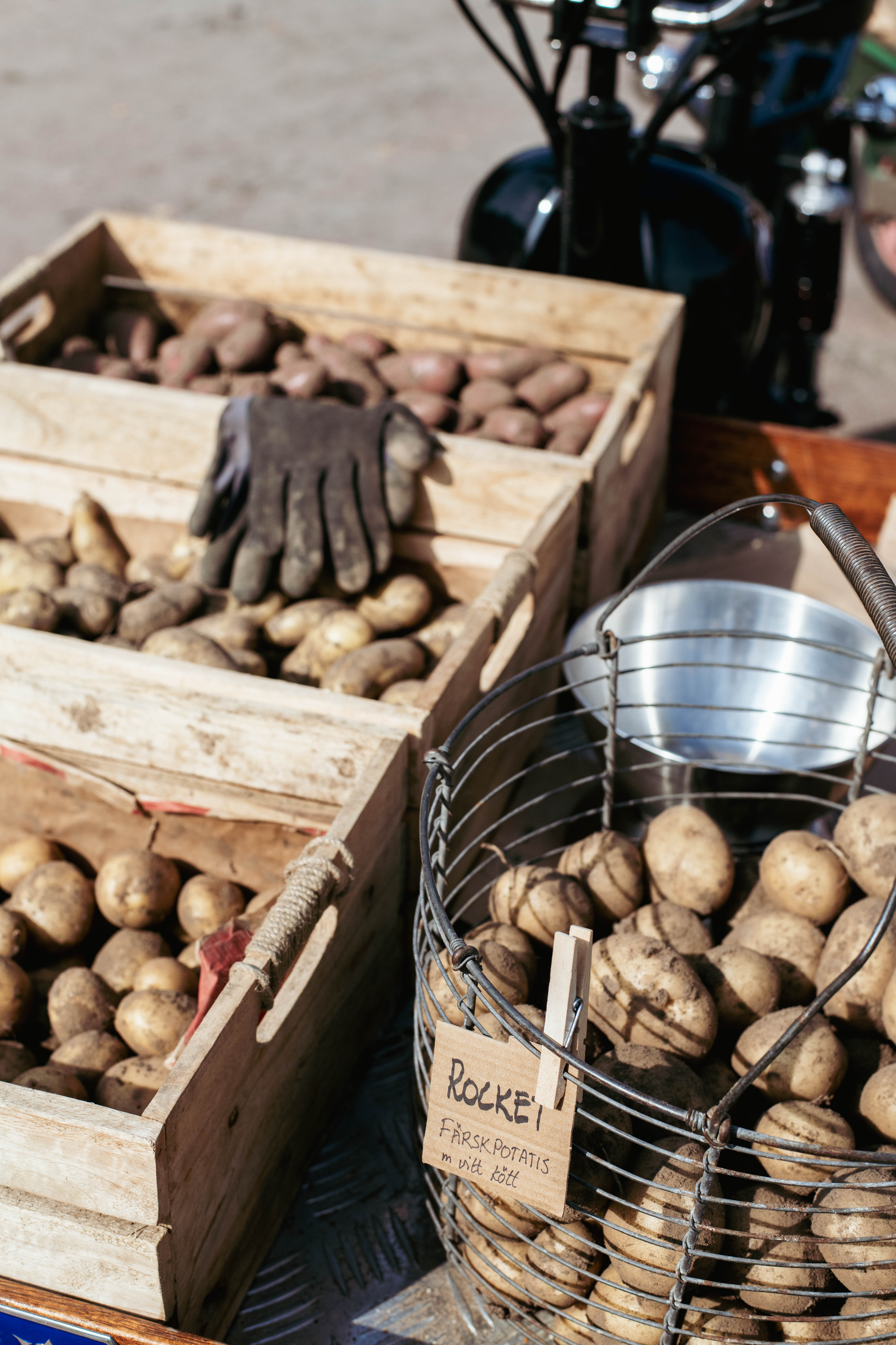 korg med potatis och tre lådor med potatis. På en av lådorna ligger ett par handskar. 