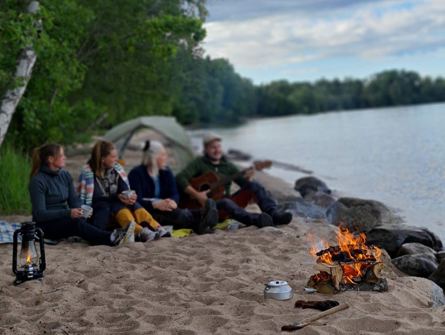 Ett gäng ungdomar fricampar på en strand. 