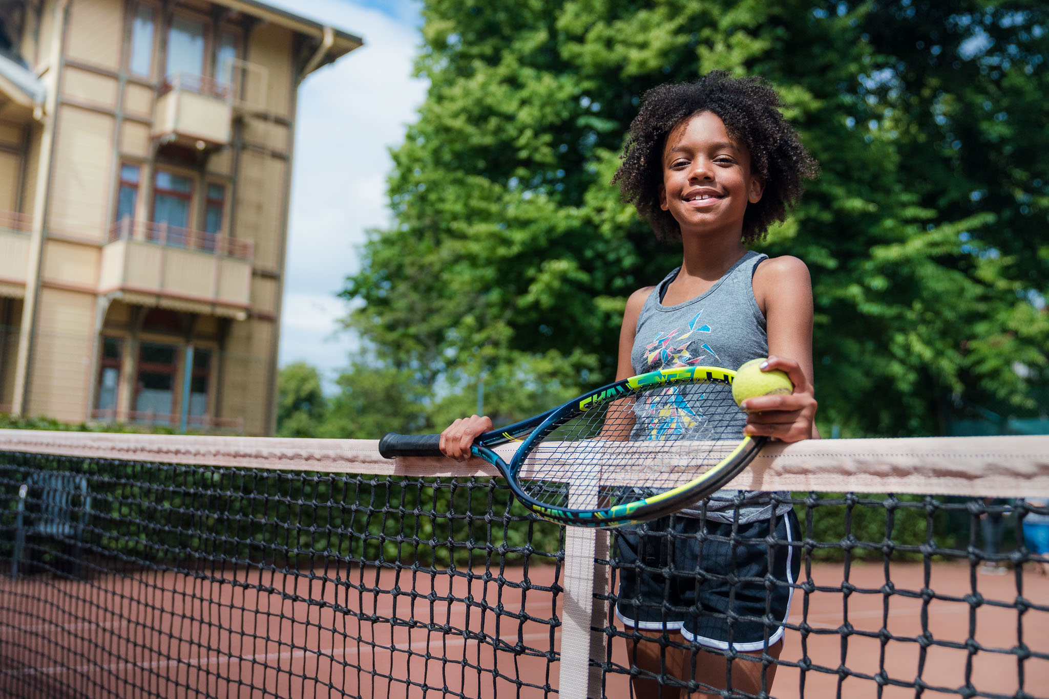 Tjej spelar tennis utomhus i Hjo Stadspark. 