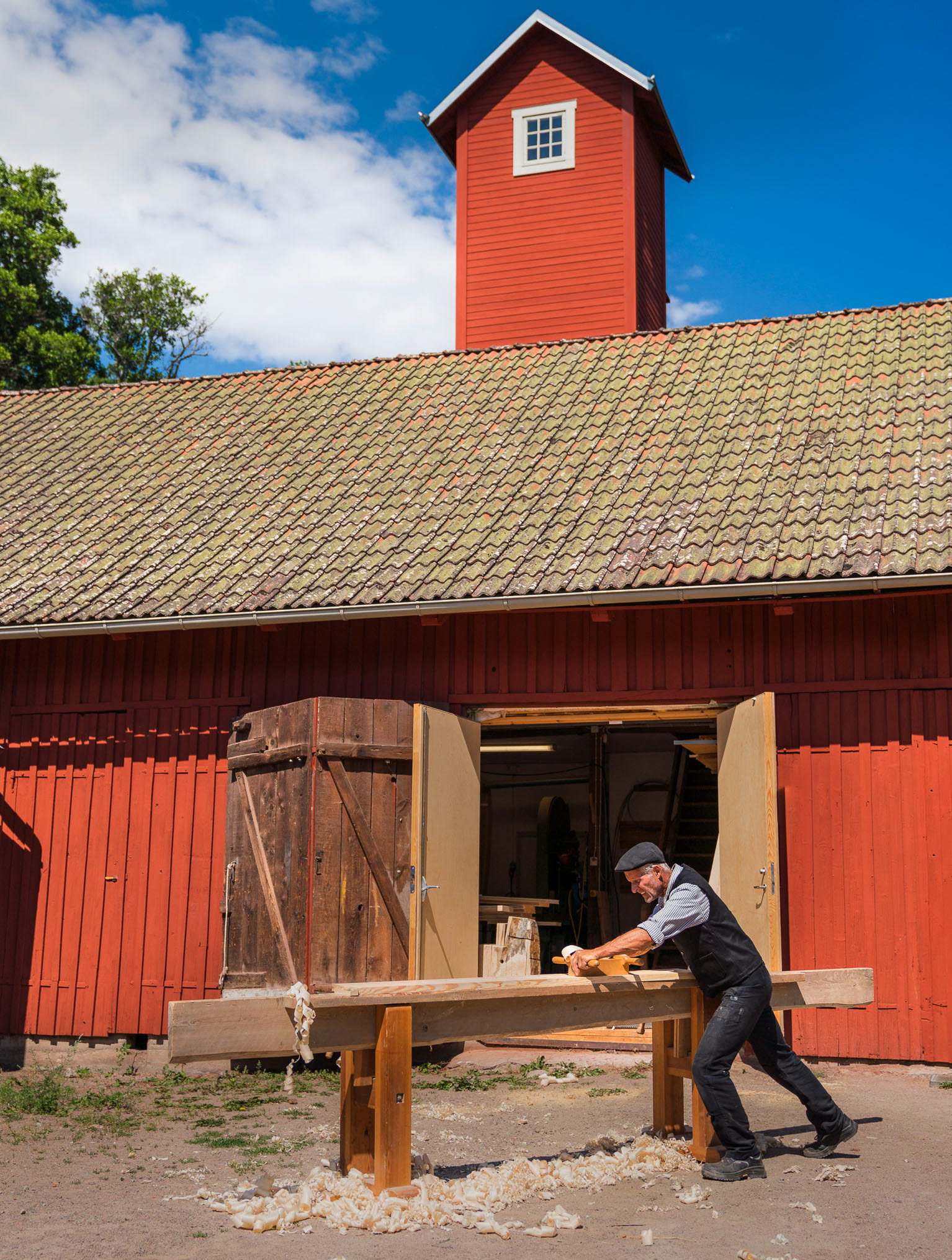 A man hand carving wood panel at the old fire station at Stadsgården in Hjo. 
