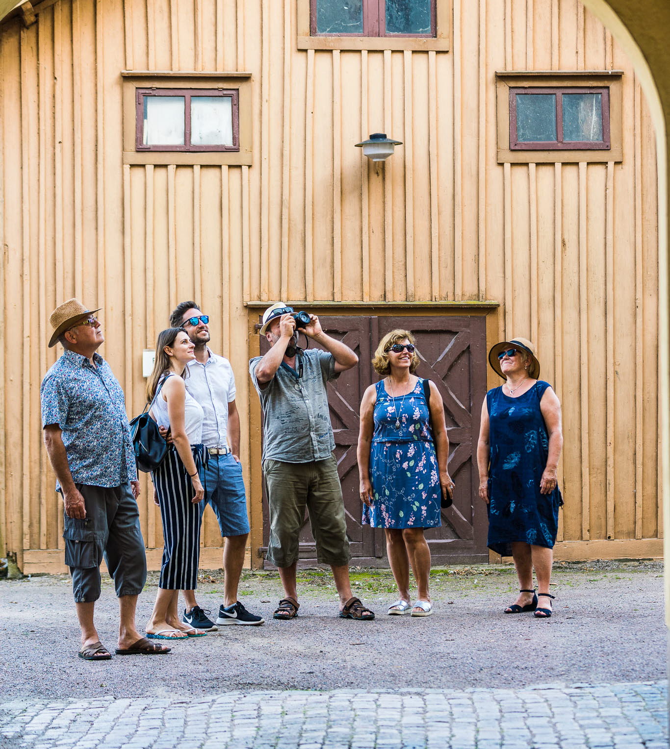 En grupp turister som fotar trähus i Hjo. 