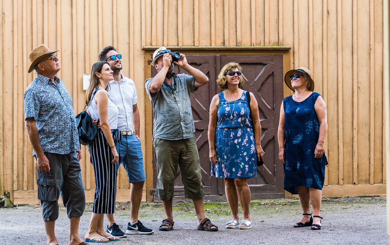 En grupp turister som fotar trähus i Hjo. 
