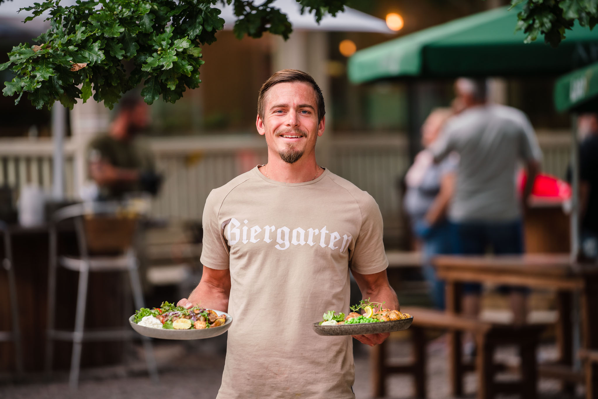 Servitör håller i två tallrikar med mat på en restaurang i Hjo. 