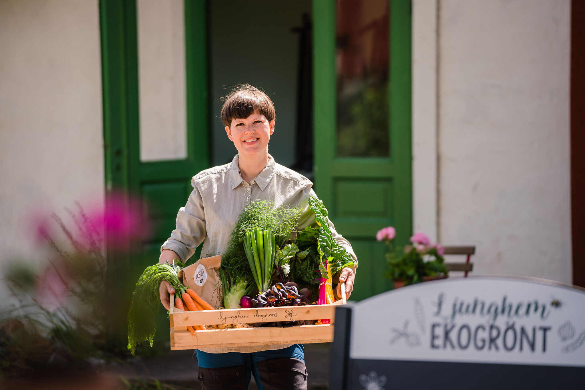 Tjej håller lokalodlade grönsaker i låda. 
