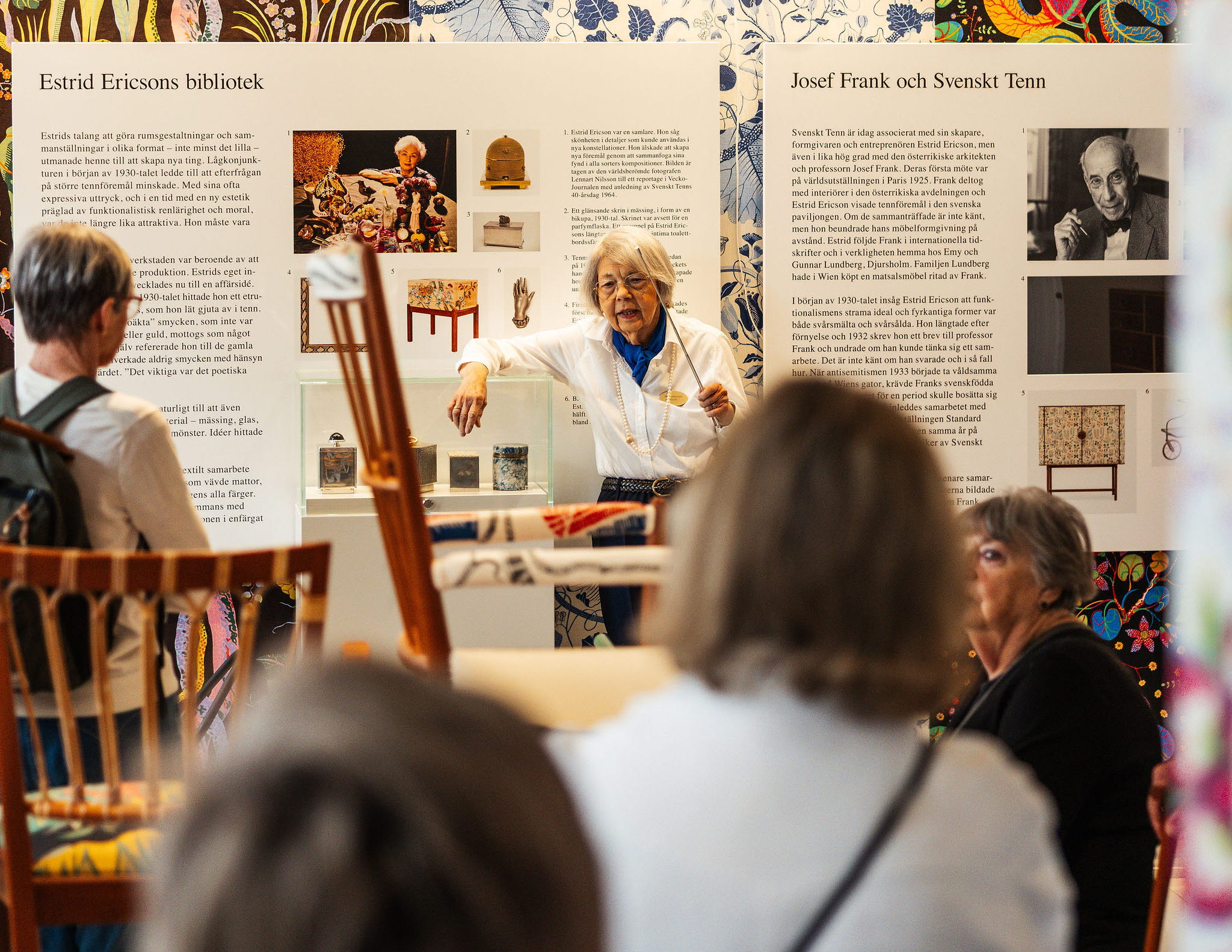 Flera personer i utställningen om Svenskt Tenn och Estrid Ericson samtidigt som en guide talar