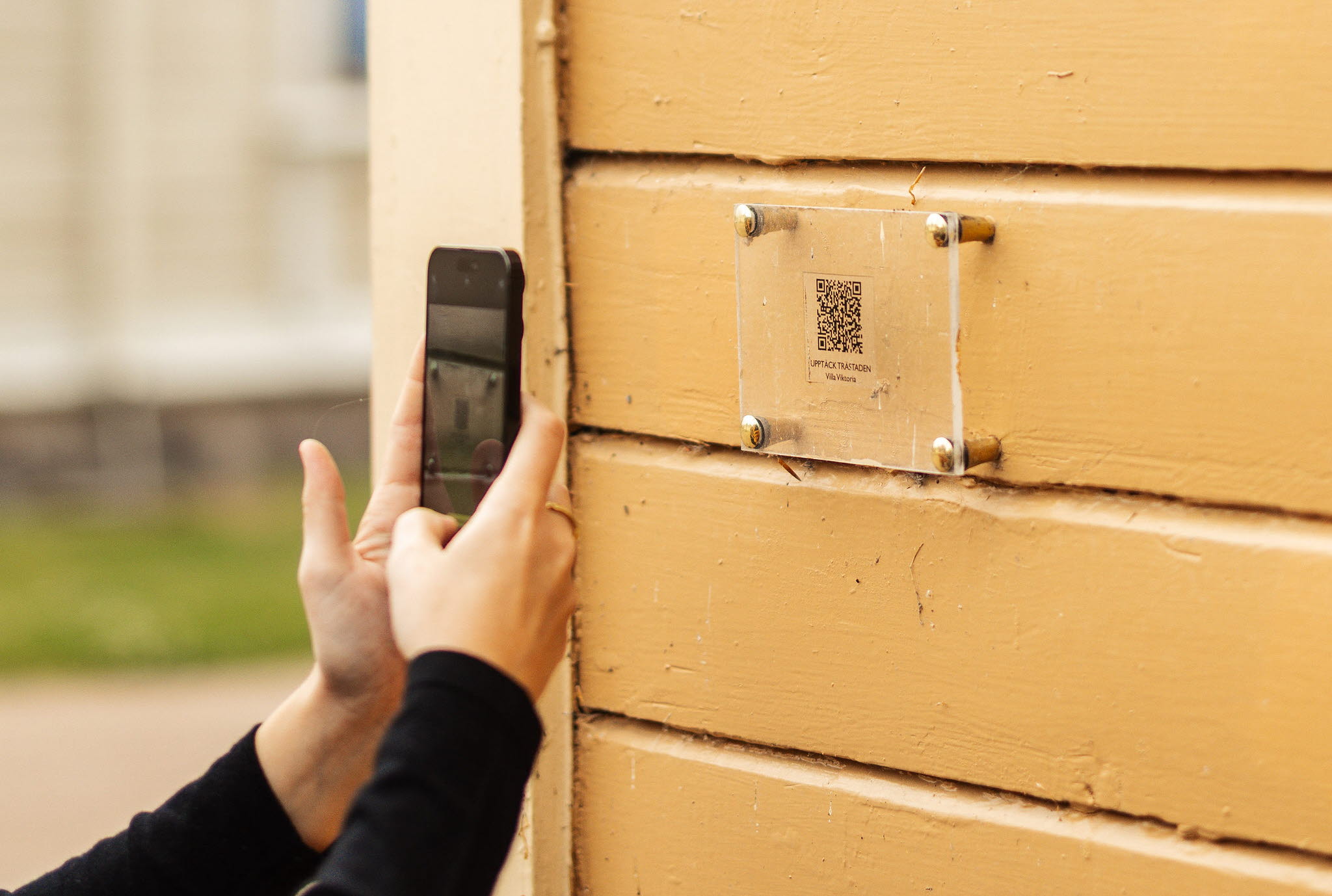 En tjej scannar en QR-kod för att lära sig mer om Kulturminnet Hjo Stadspark