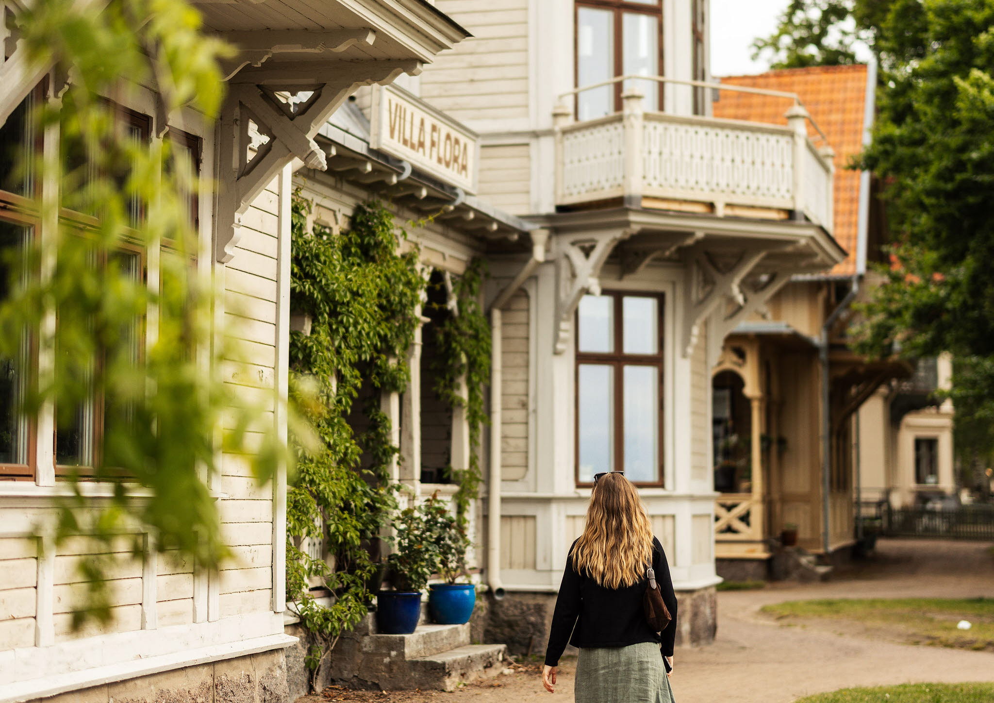 En tjej promenerar förbi en av trävillorna i Hjo stadspark