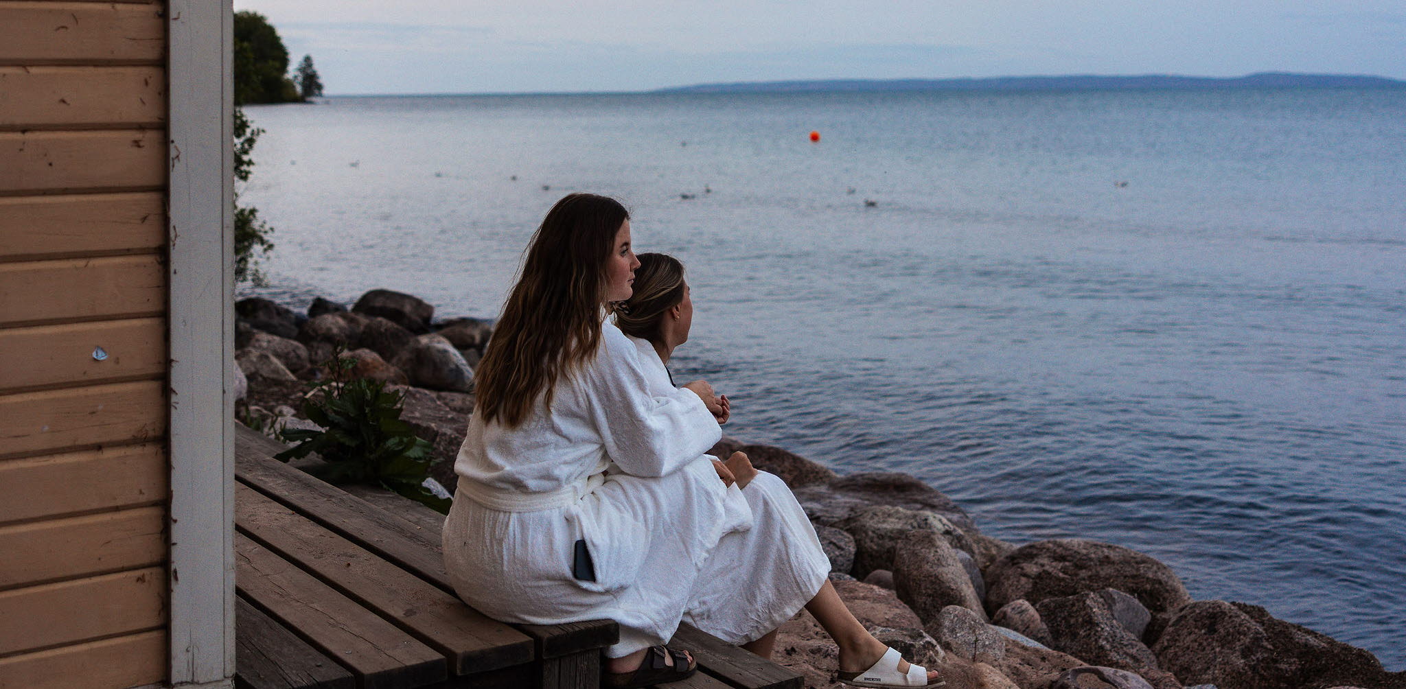 En grupp personer njuter av bastun vid Vätterns strand i Hjo