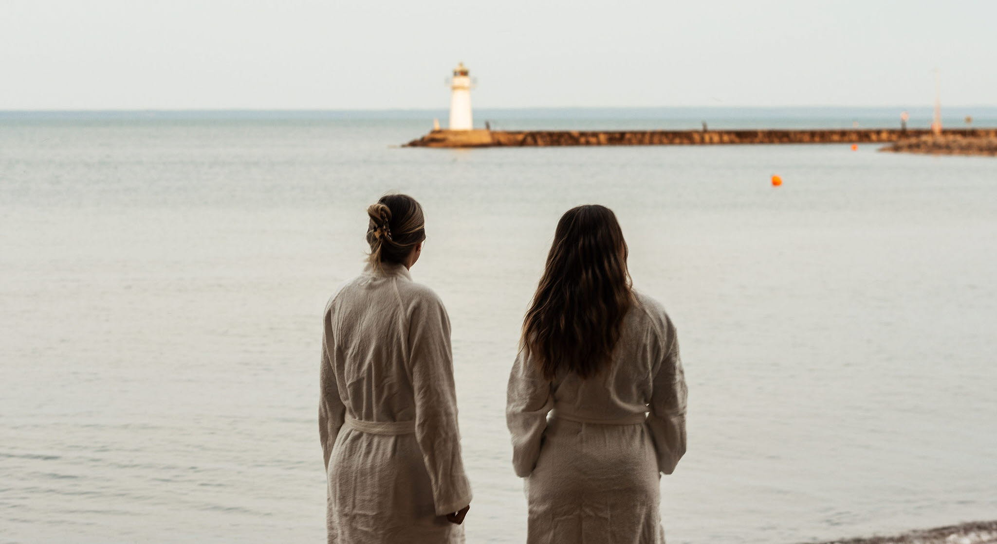 En grupp personer njuter av bastun vid Vätterns strand i Hjo