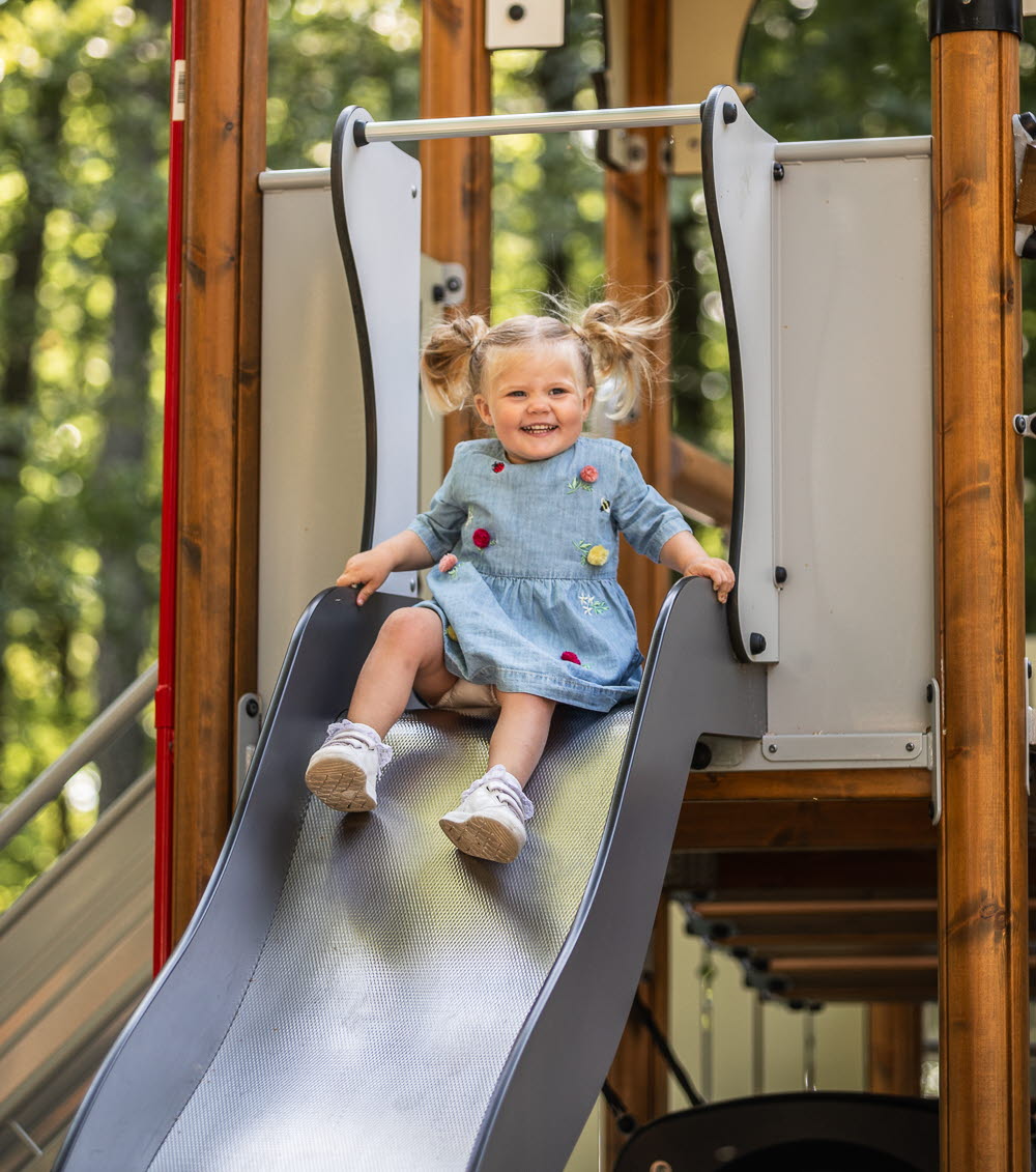 En flicka åker rutschkana på en lekplats. 