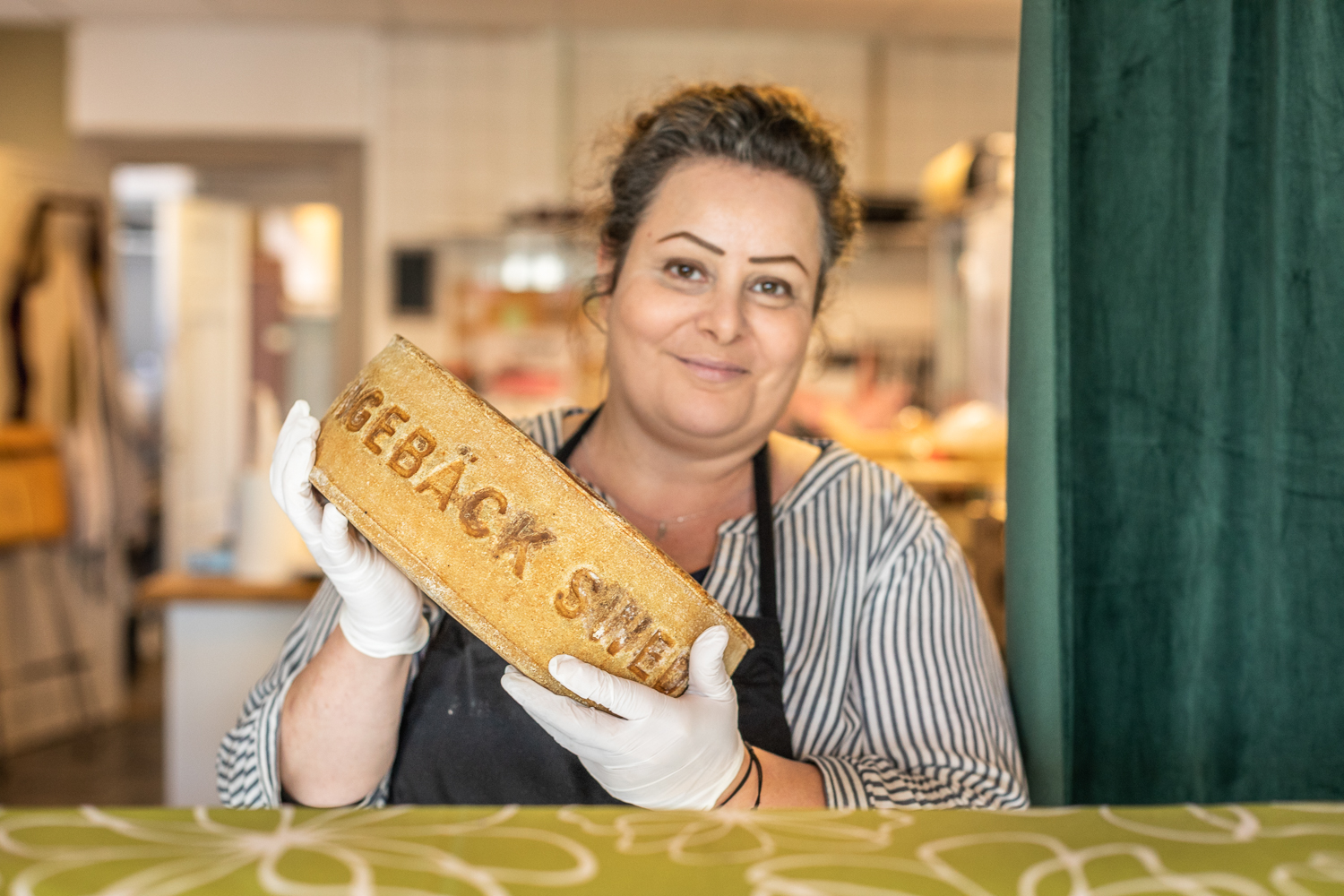 En kvinna står och håller i en stor ost över en disk. 