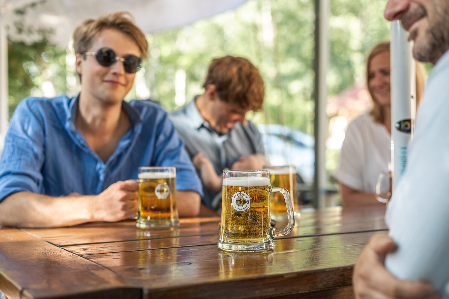 Ett gäng sitter och dricker öl vid ett träbord. 