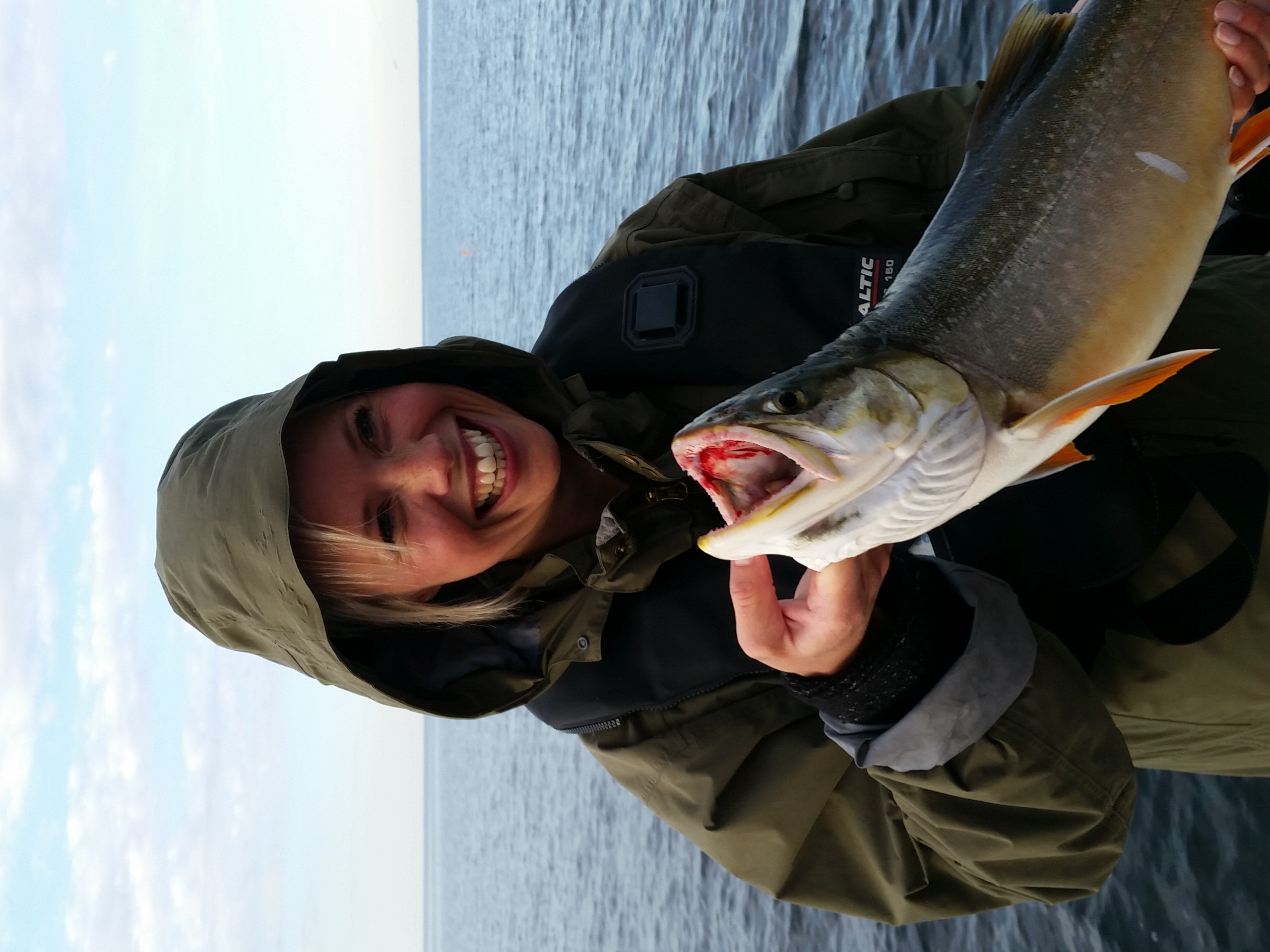 Kvinna på trollingfisketur på Vättern, med nyfångad Gädda i händerna. 