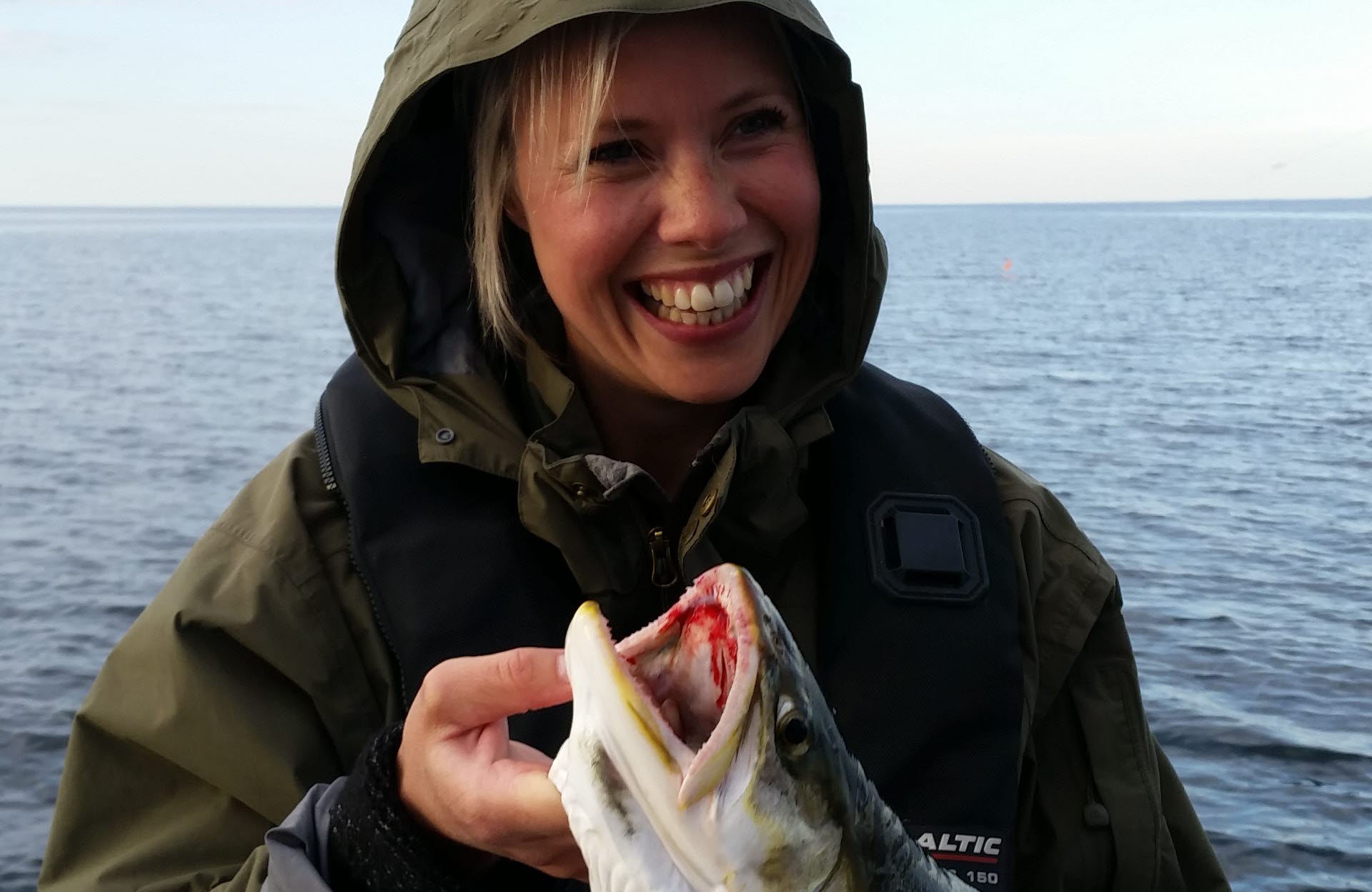 Woman on a fishing tour on lake Vättern, haveing caught a pike. 