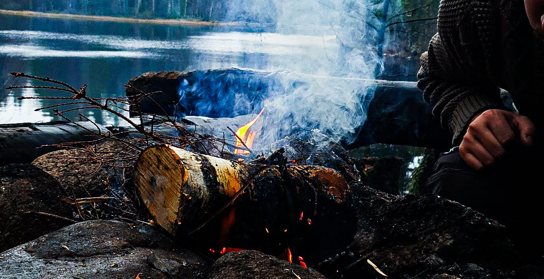 Kille vid en eld i skogen. 