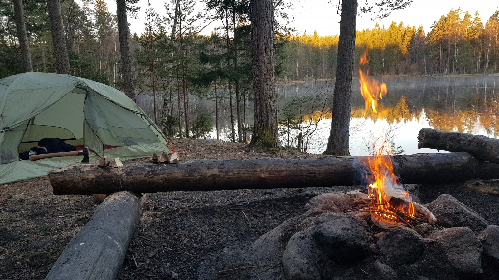 Eldplats och tält vid en sjö.