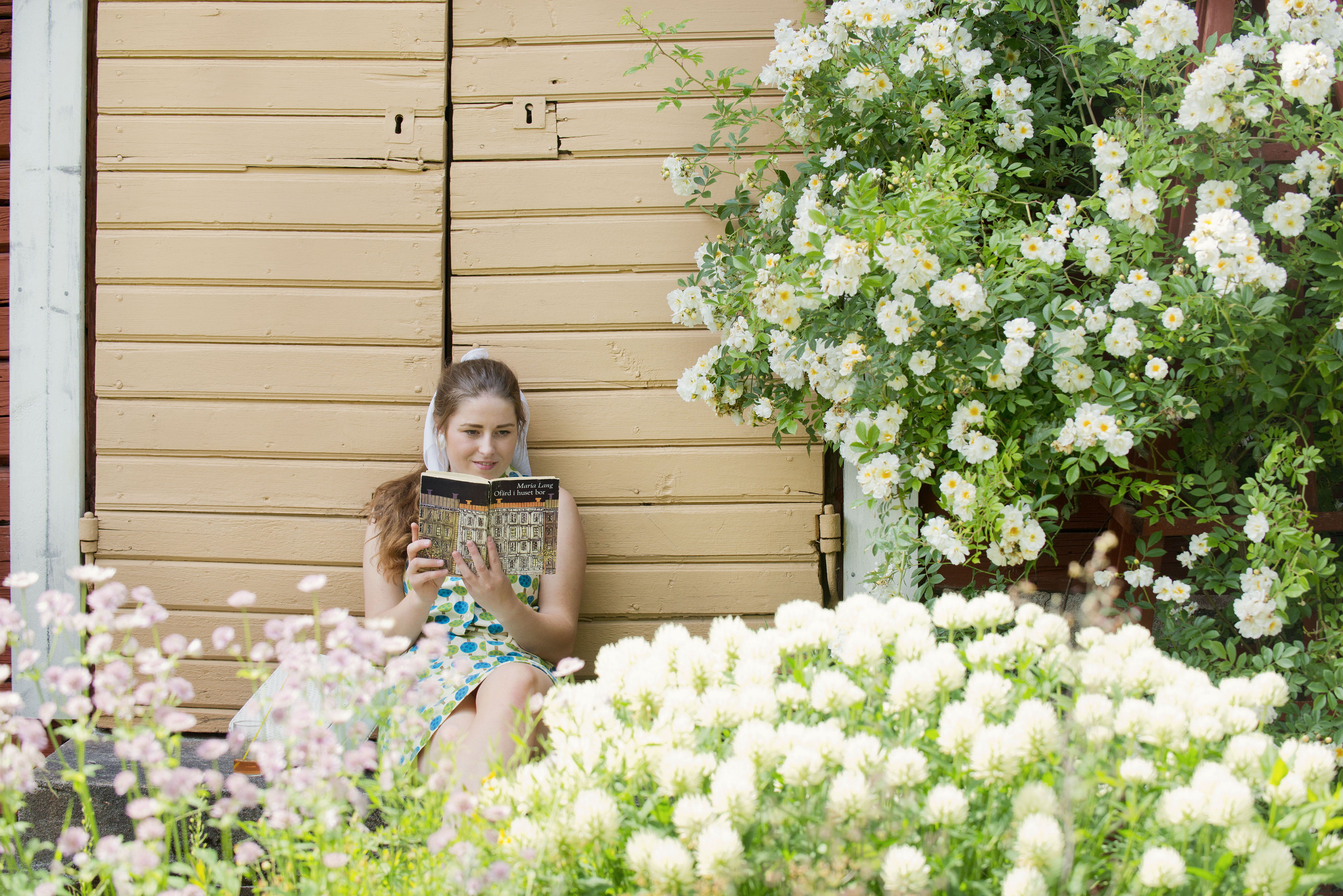 Kvinna läser Maria Lang på en bakgård i Nora-