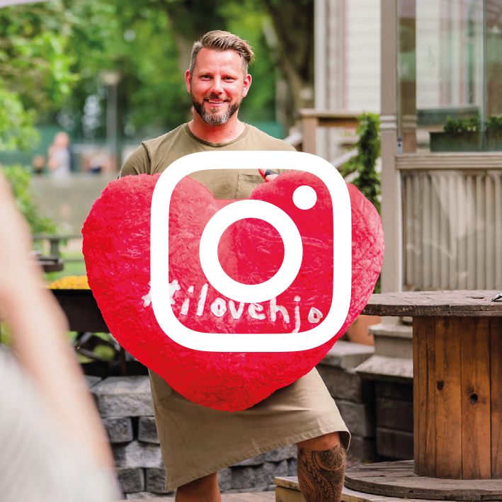 Guy holding up a giant I love Hjo heart in Hjo. 