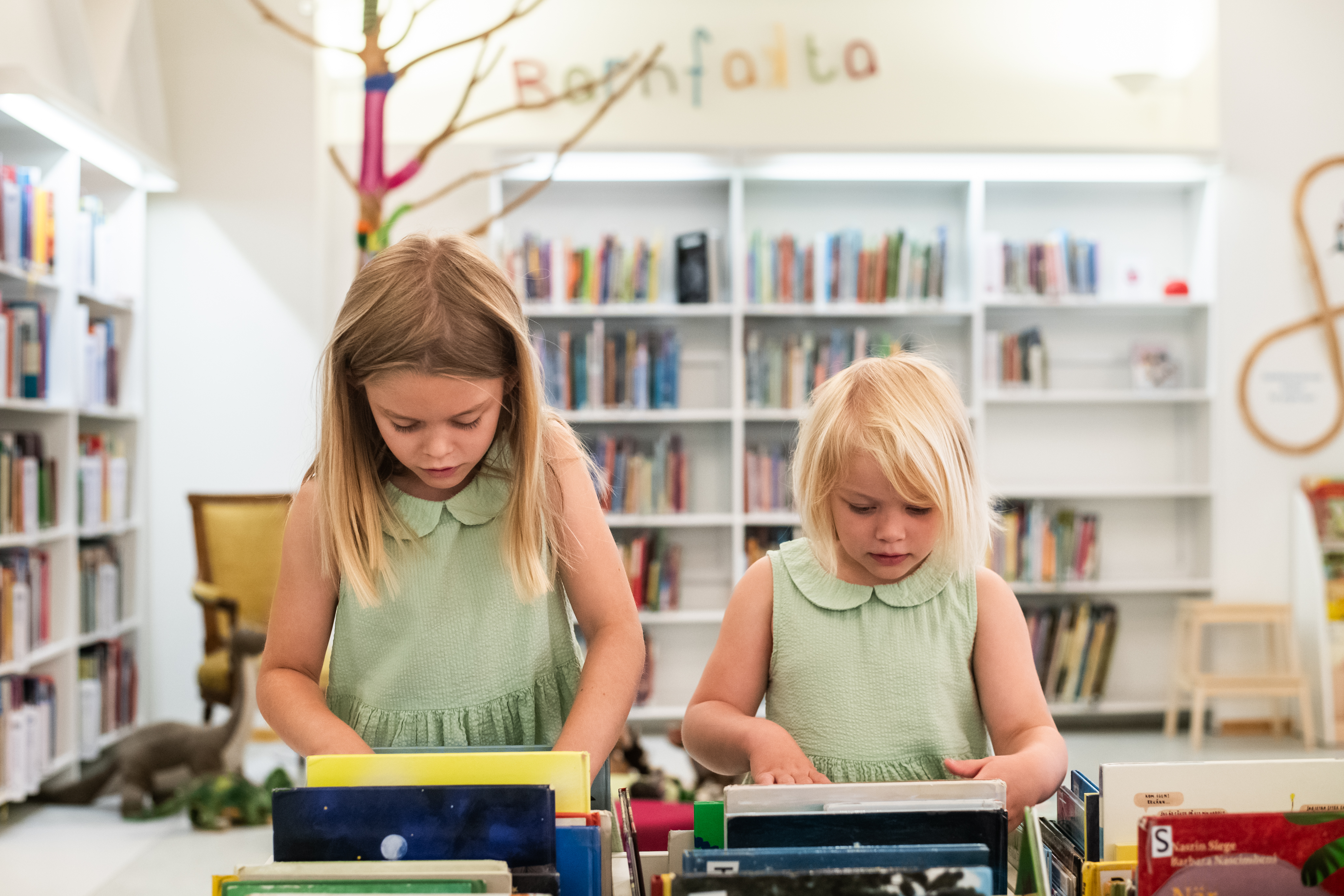 Två barn letar efter böcker i ett bibliotek.