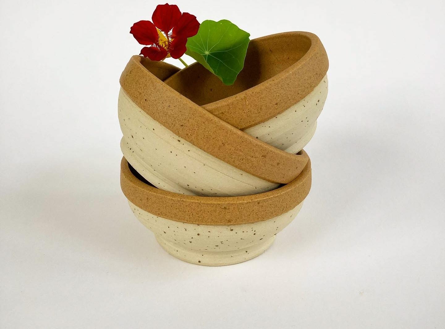 Handdrejade djupa tallrikar i beige-brunt som ligger på varandra