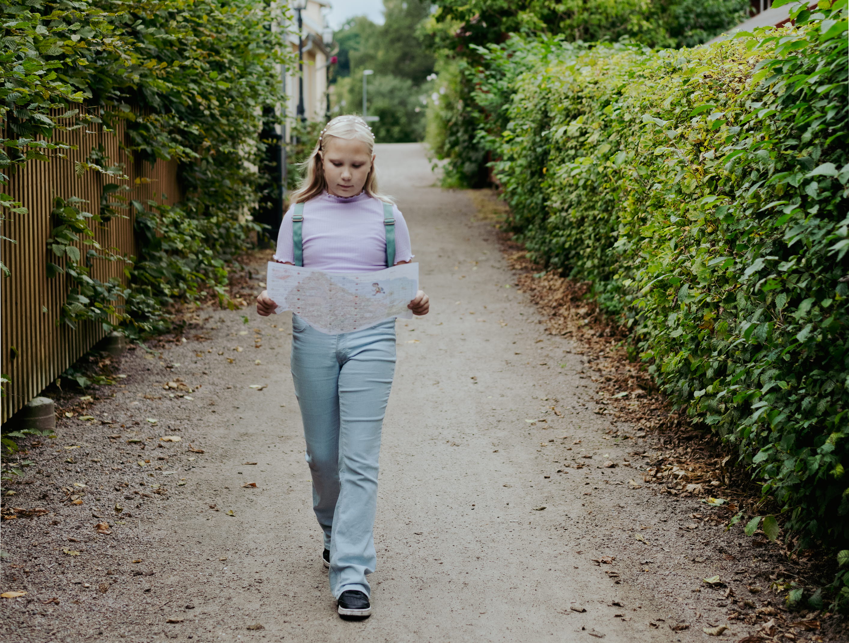 Barn går i en grusgång med en karta i handen