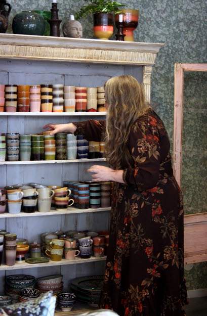 Marie justerar bland keramikmuggar i en hylla