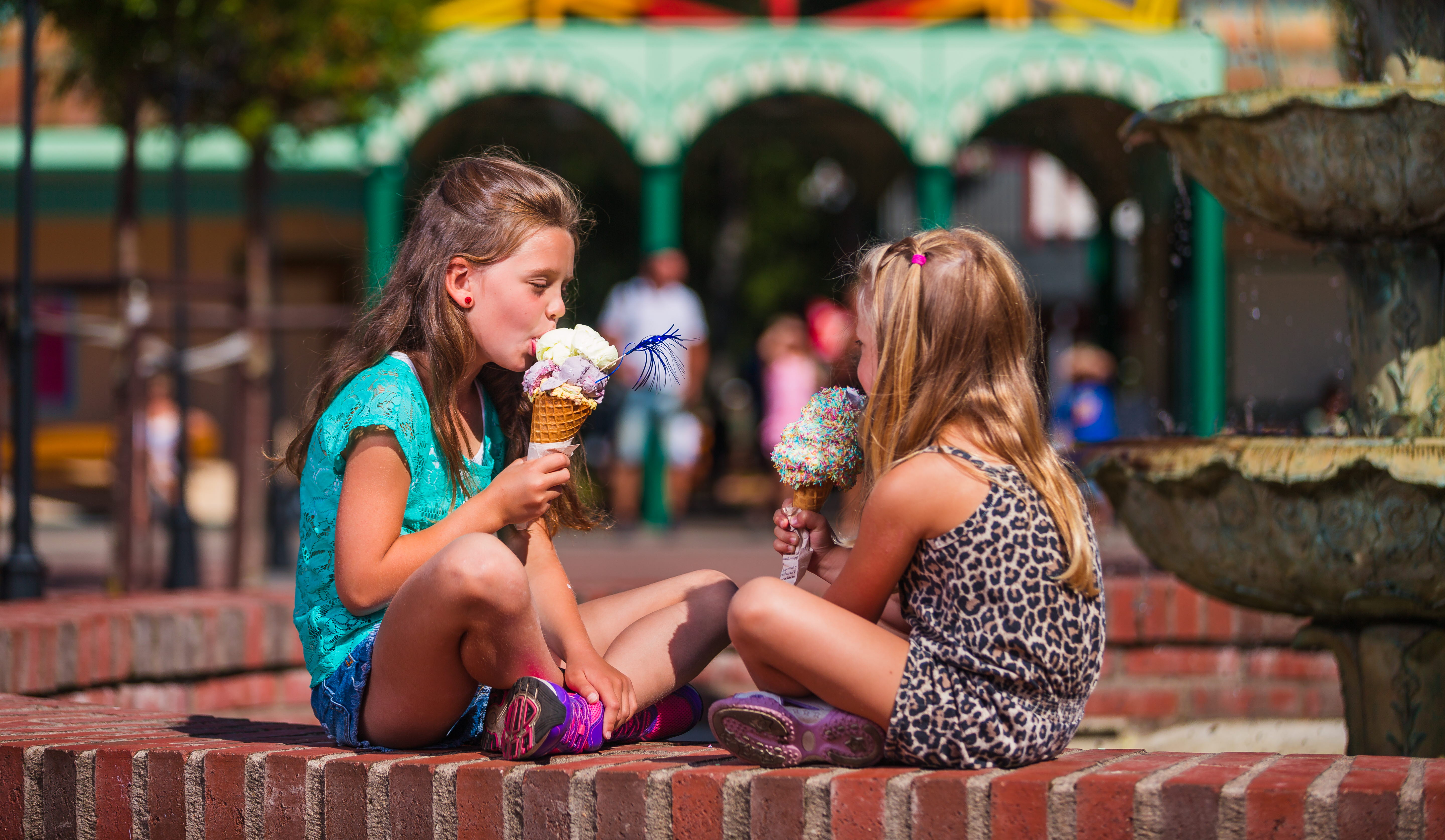 Två barn äter glass på en mur.