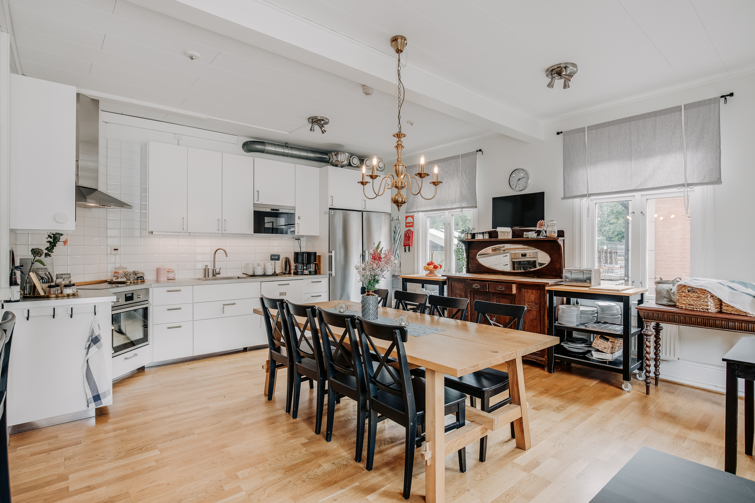Kitchen with table and chairs. White doors in the kitchen and two windows with gray curtains.