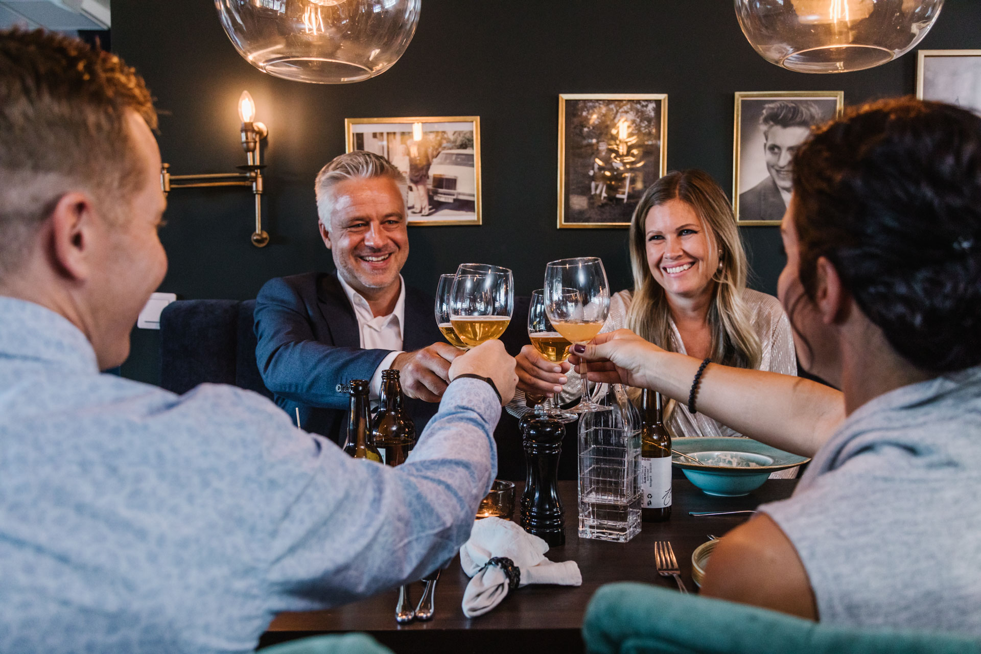 Fyra personer sitter vid ett matbord och skålar.