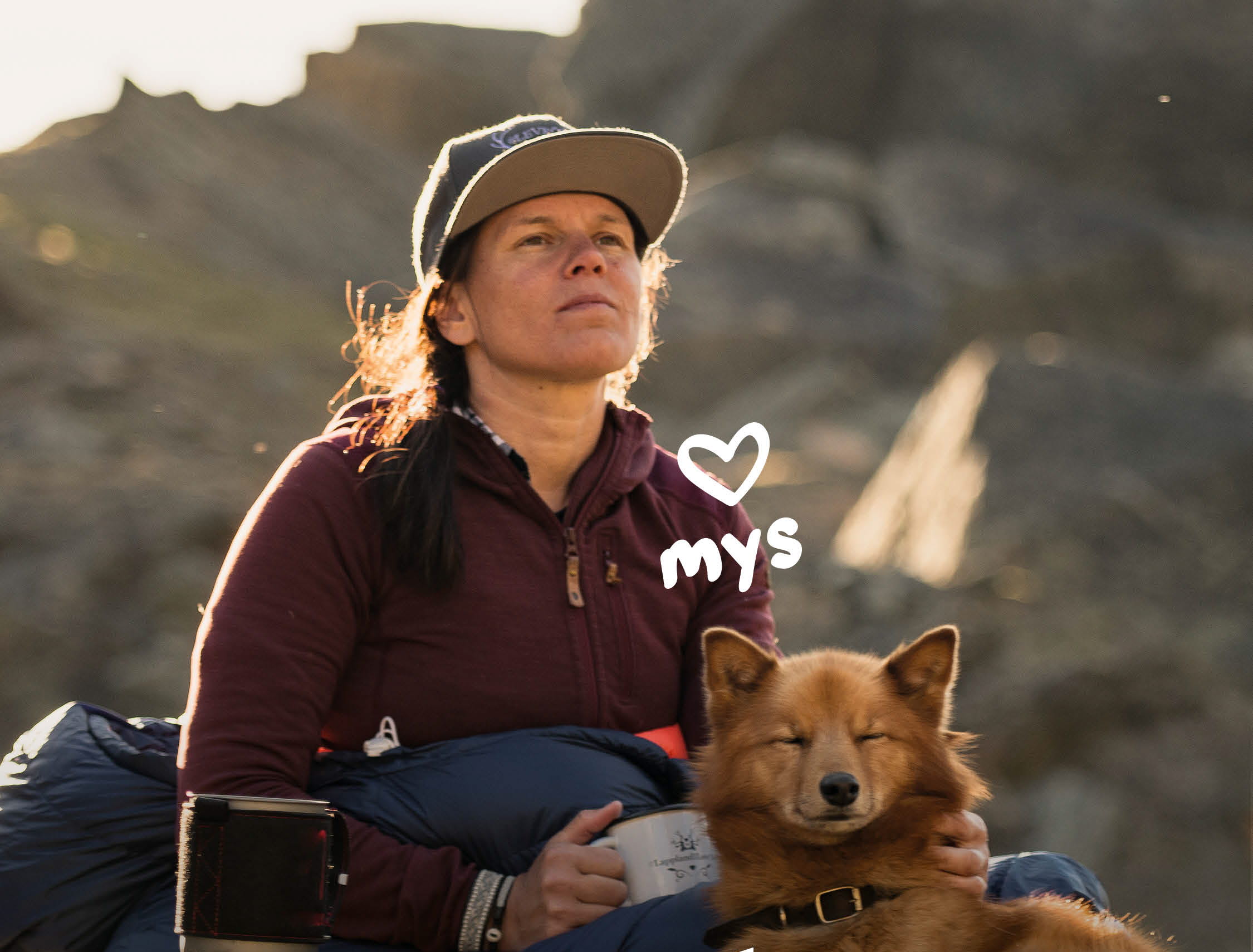 En kvinna som sitter med sin hund på marken med en kopp kaffe.