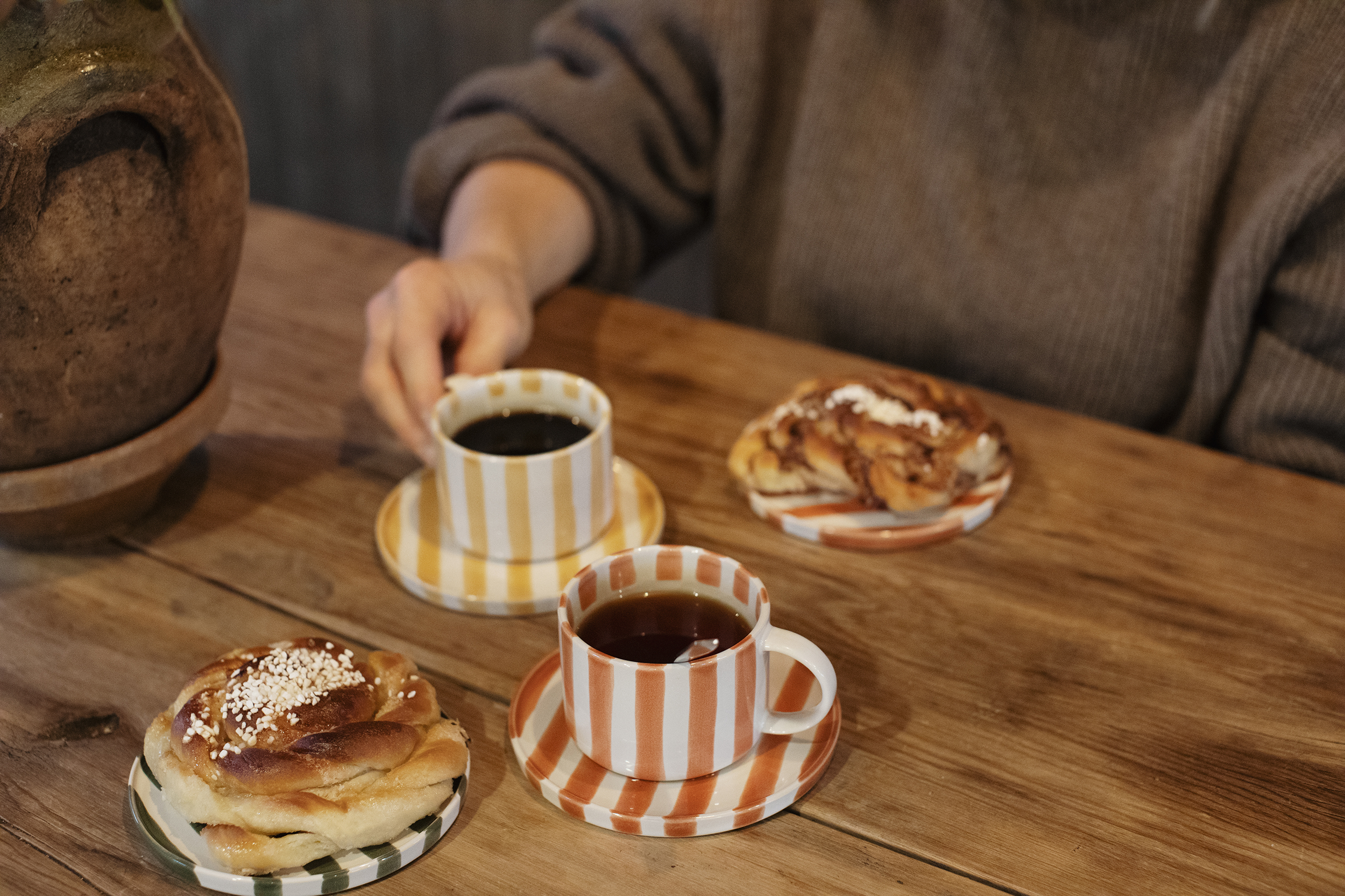 Två randiga kaffekoppar och två fat med bullar. 