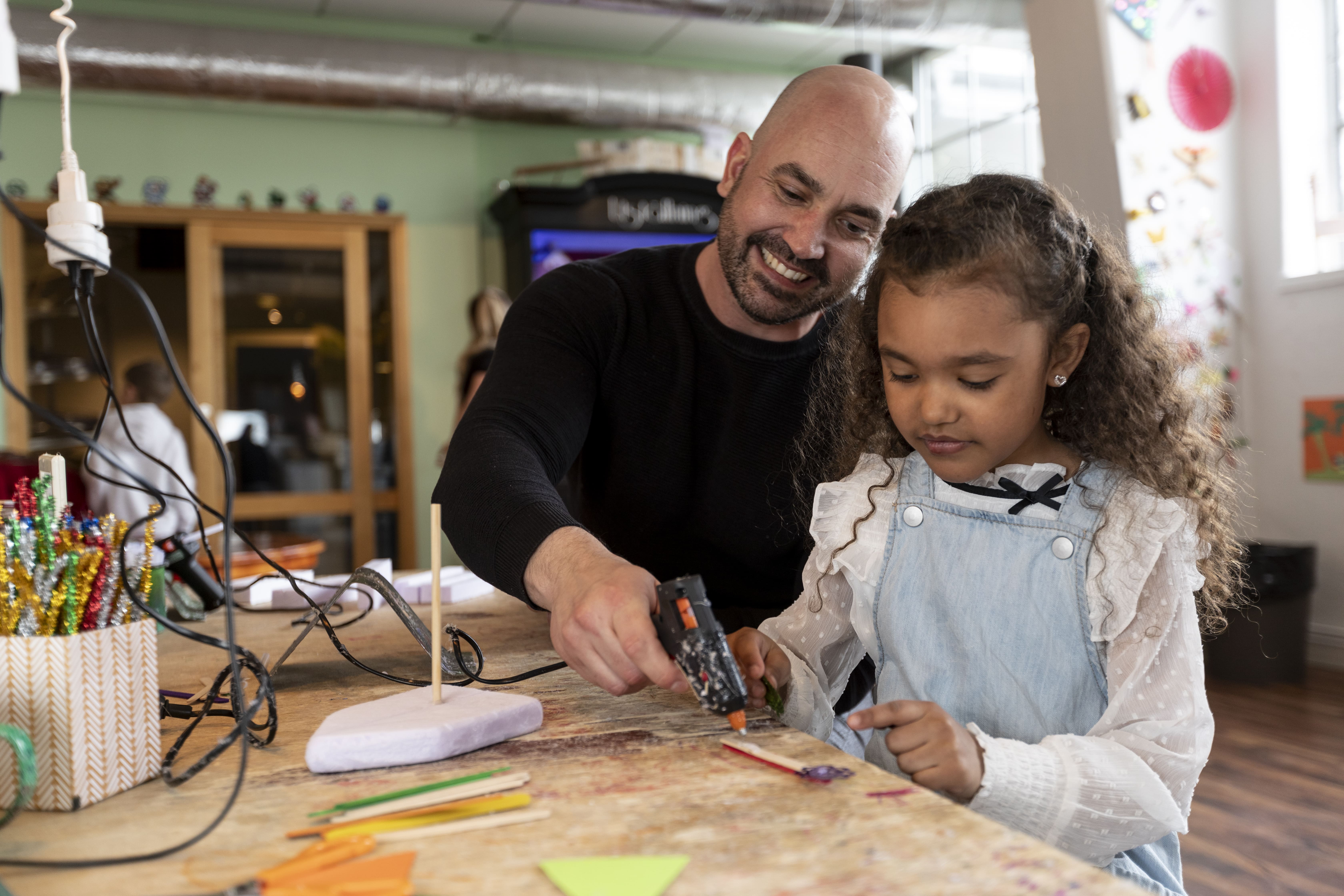 En pappa och en flicka som sitter och pysslar vid ett bord.