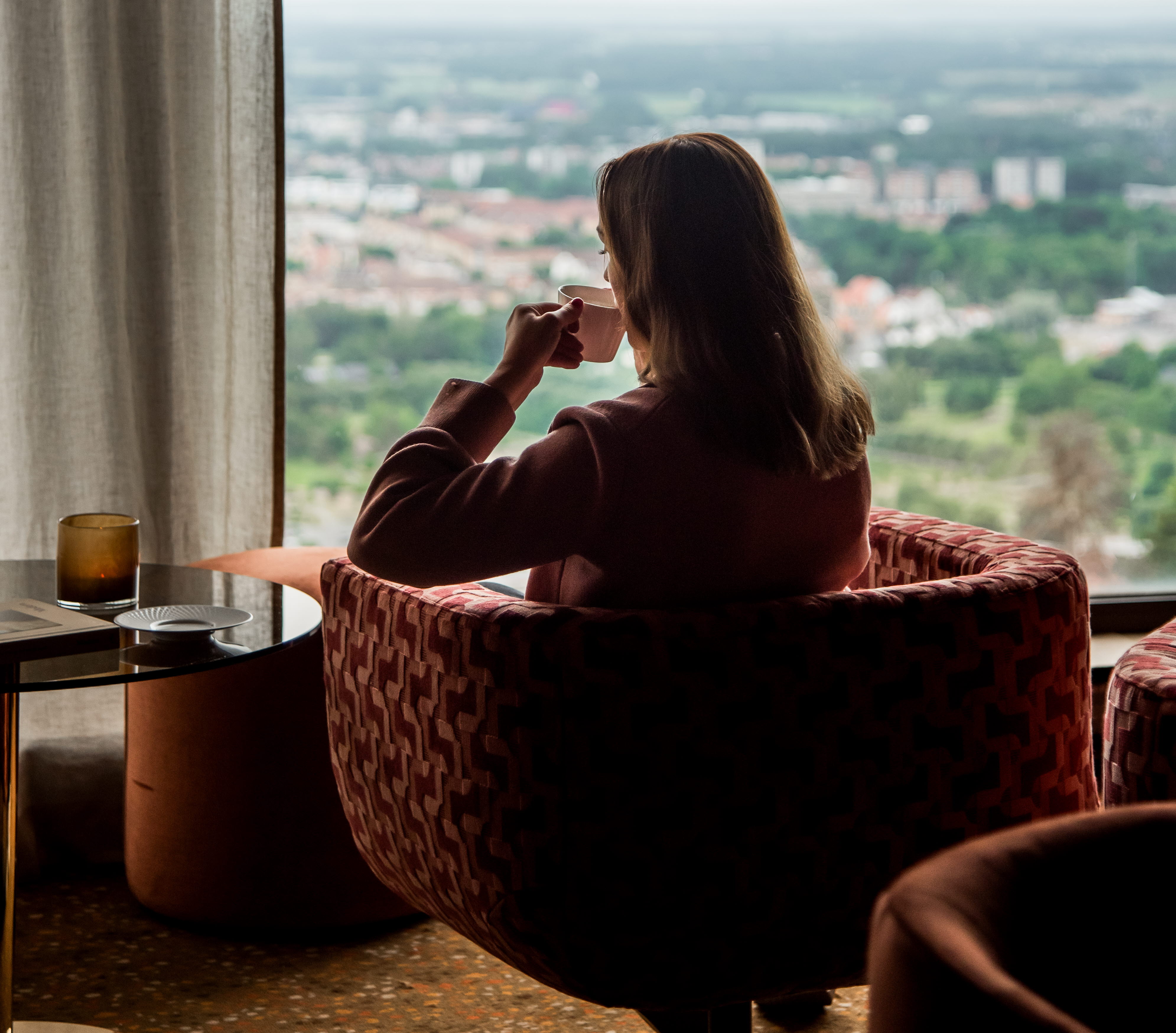 Woman sitting in an armchair and looking out a window.