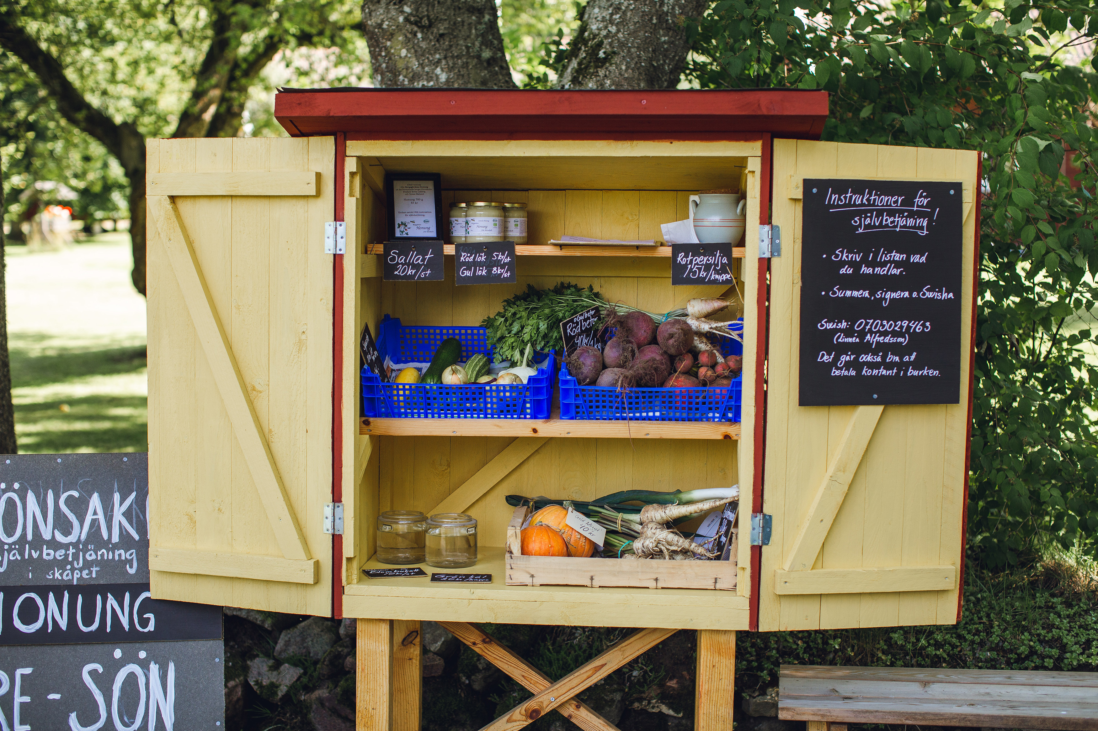 Träskåp med öppna dörrar. I skåpet finns grönsaker och frukt.