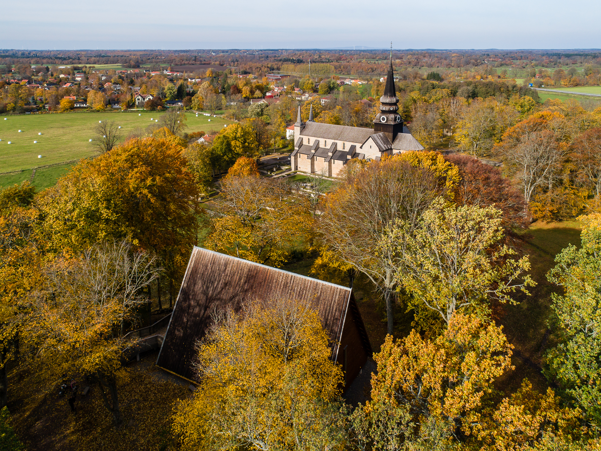 Drone picture over a mighty stone church. The trees have yellow autumn leaves. 