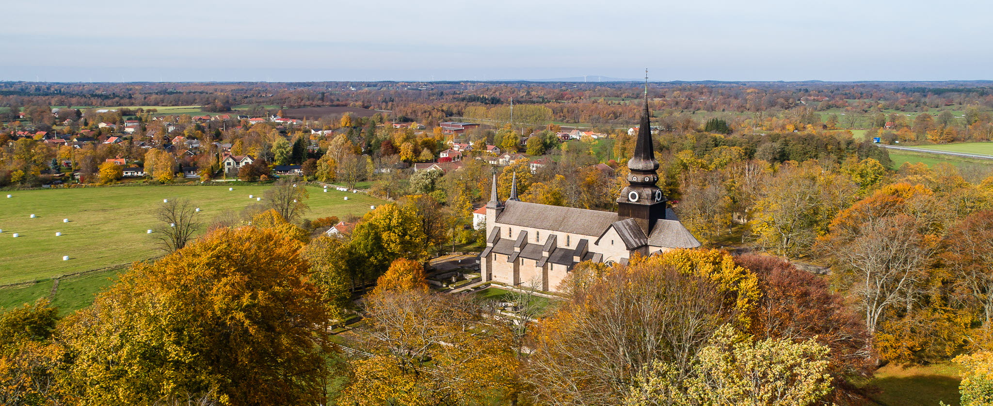 Drone picture over a mighty stone church. The trees have yellow autumn leaves. 