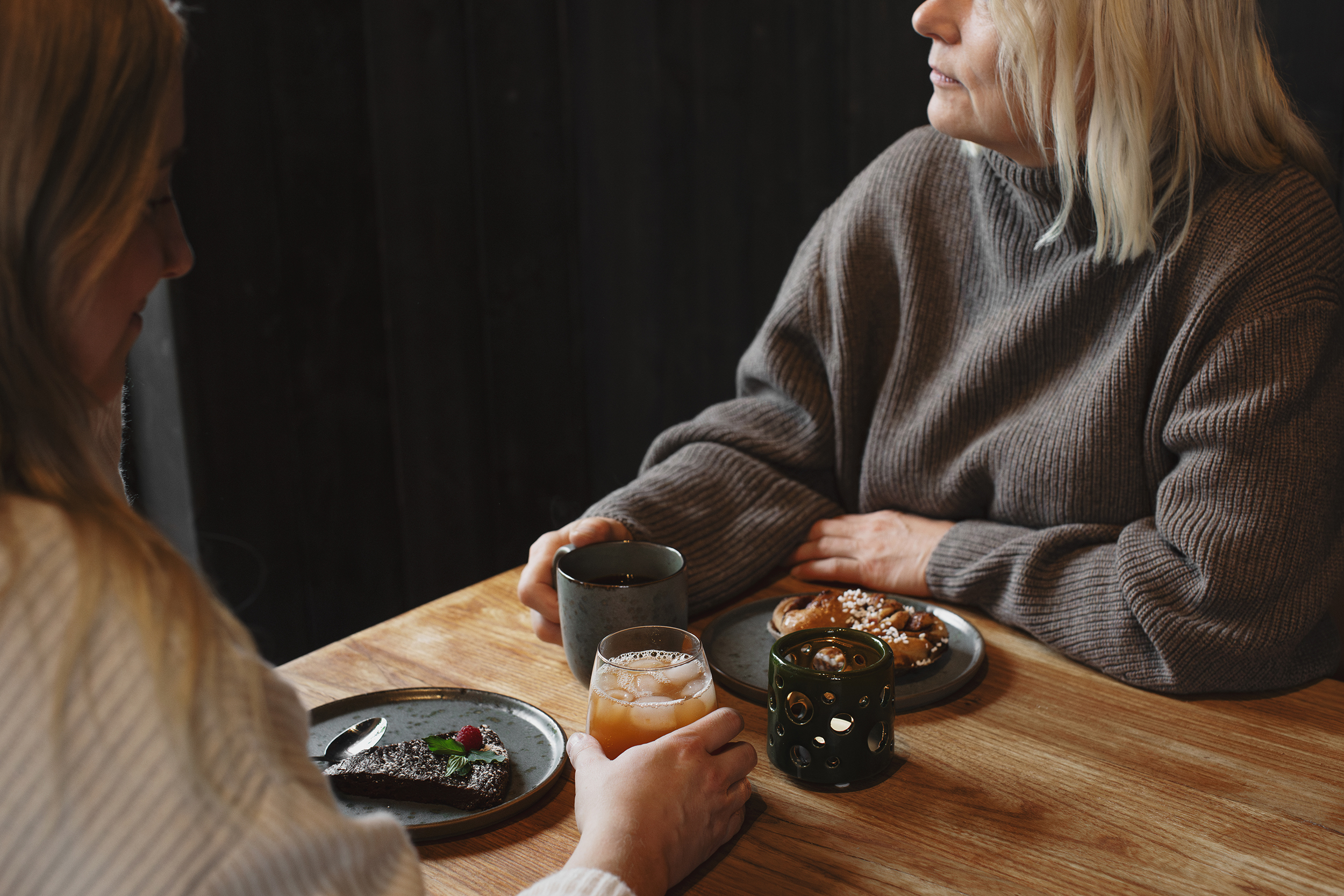 två kvinnor sitter och fikar vid ett bord. 