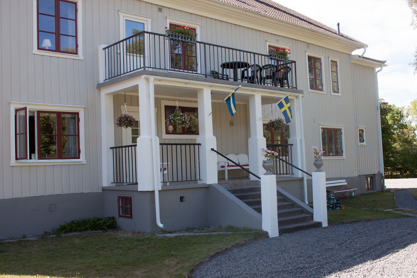 Entrén på Pensionat Klåvasten, en större vit träbyggnad med röda fönster. 