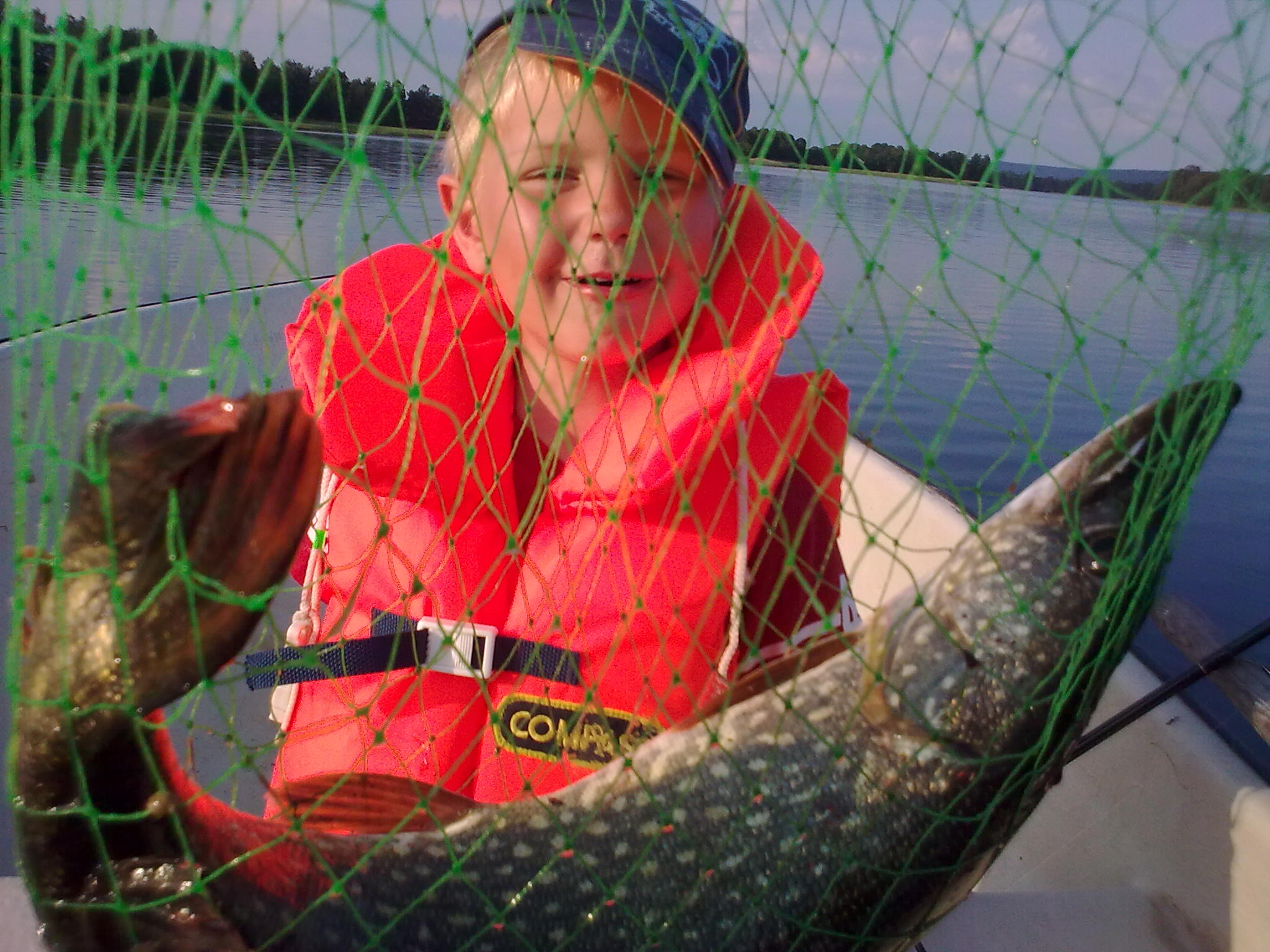 Pojke som sitter med en gädda i en håv.