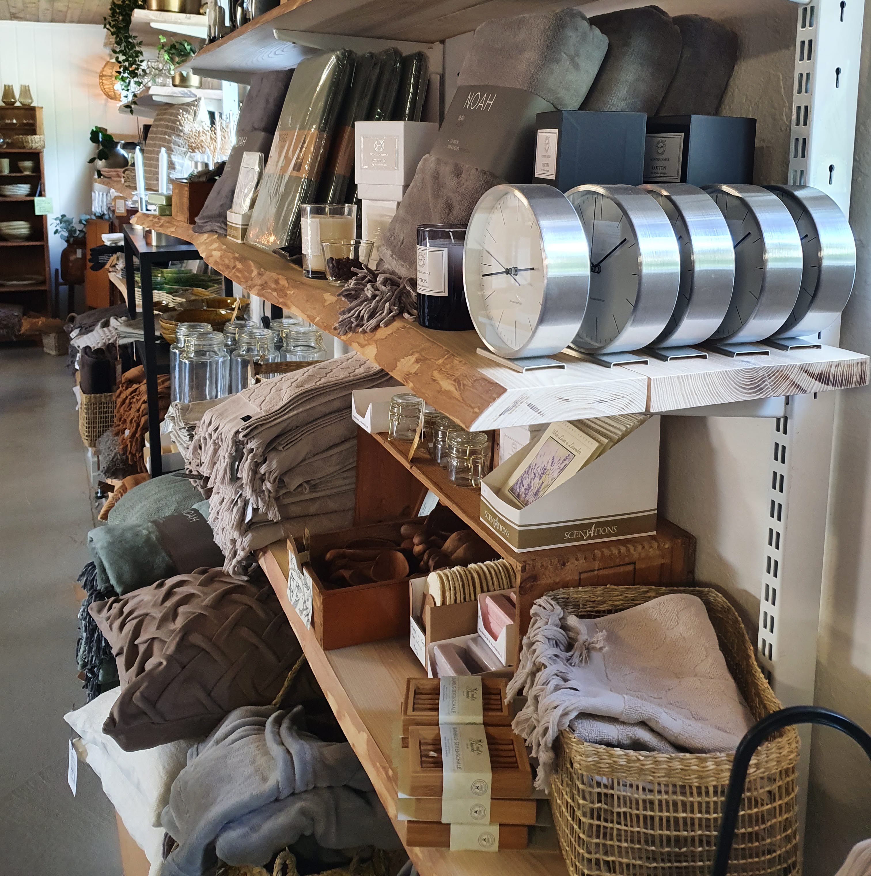 Tre hyllor i trä med olika inredningsprylar på t ex. kuddar och ljuslyktor.