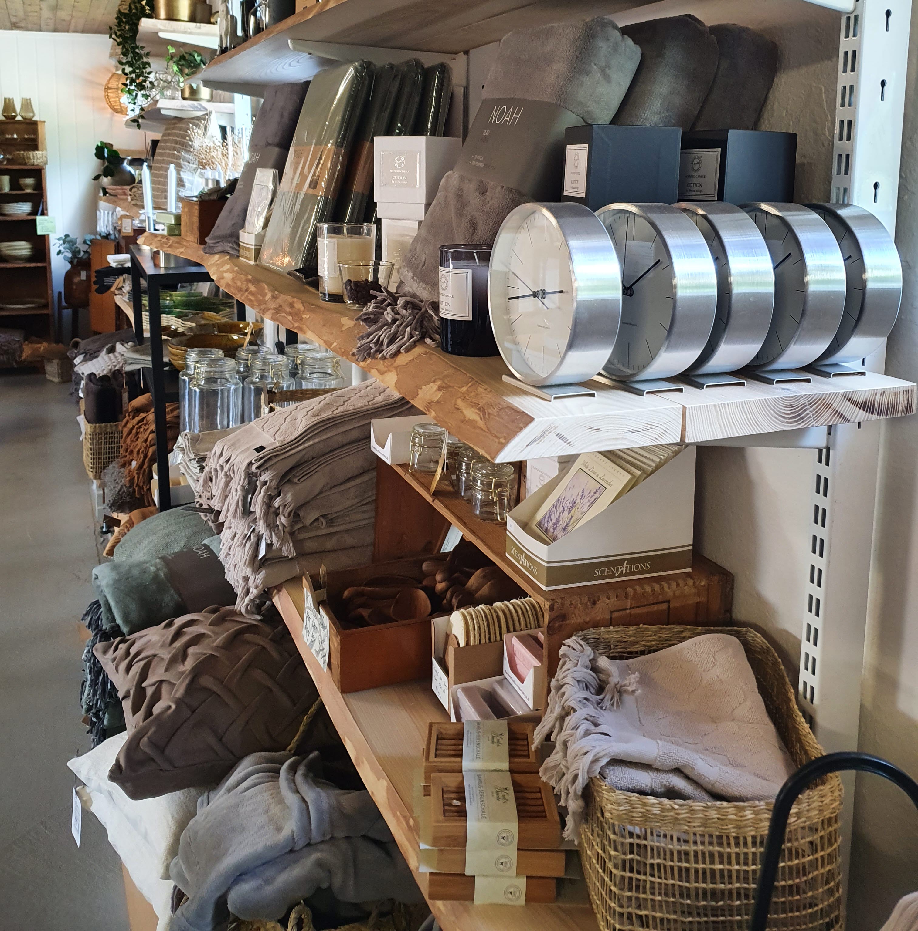 Tre hyllor i trä med olika inredningsprylar på t ex. kuddar och ljuslyktor.