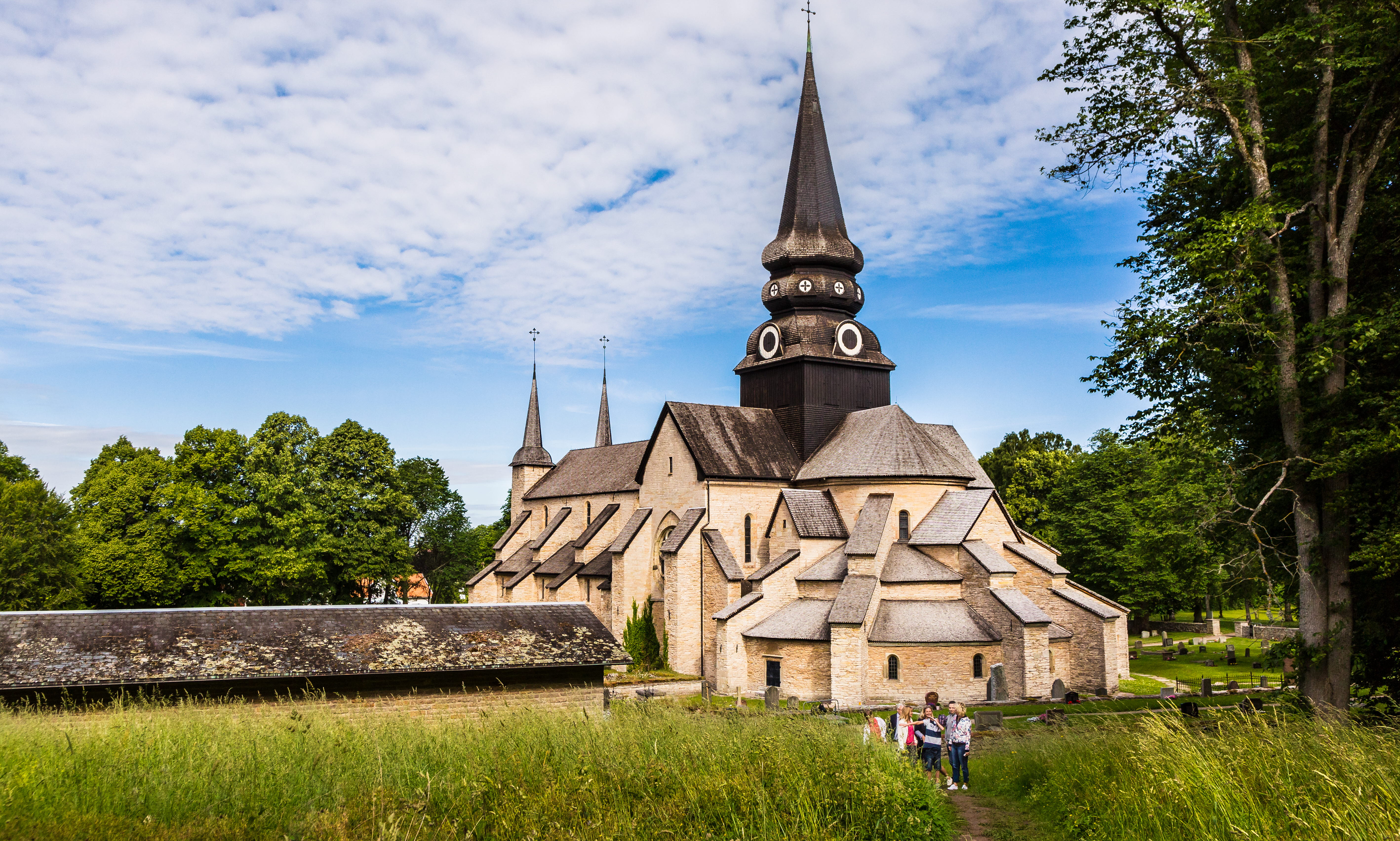 Varnhems klosterkyrka. I förgrunden syns vandrare gå mot den imponerande stenkyrkan.