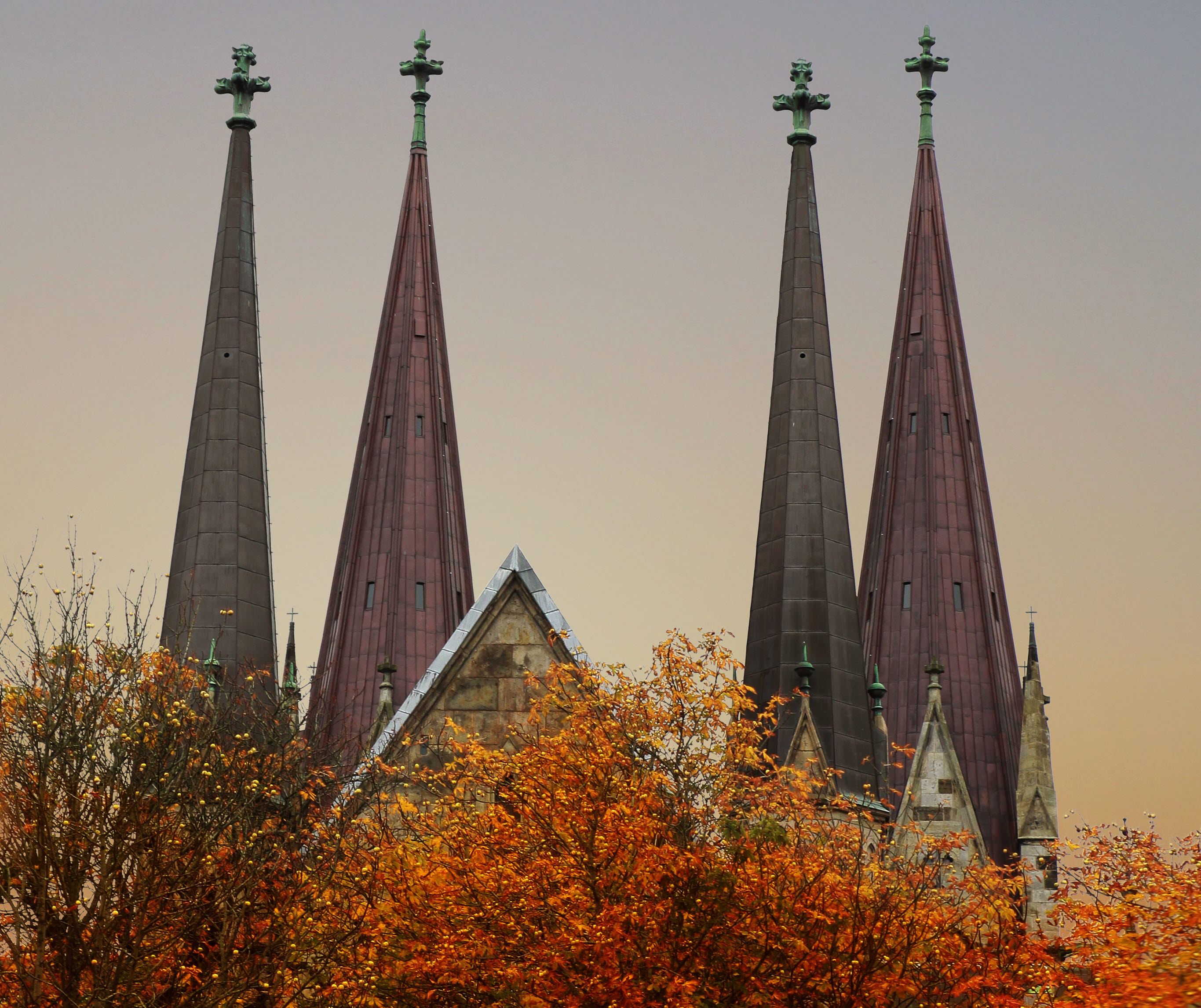 Red autumn trees in front of the church towers on Skara domkyrka. 