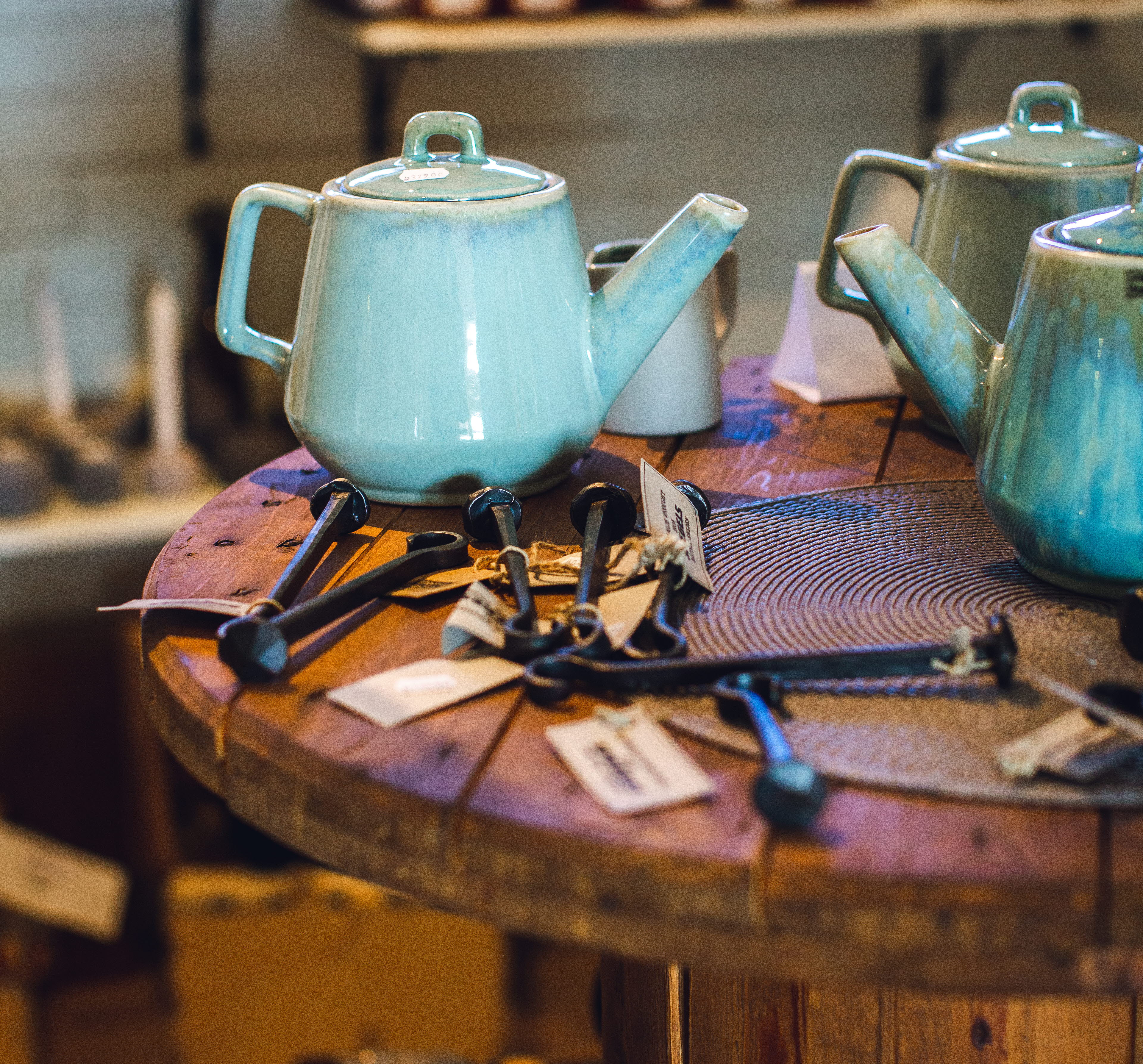 Några kaffekannor i turkost porslin på ett runt träbord.