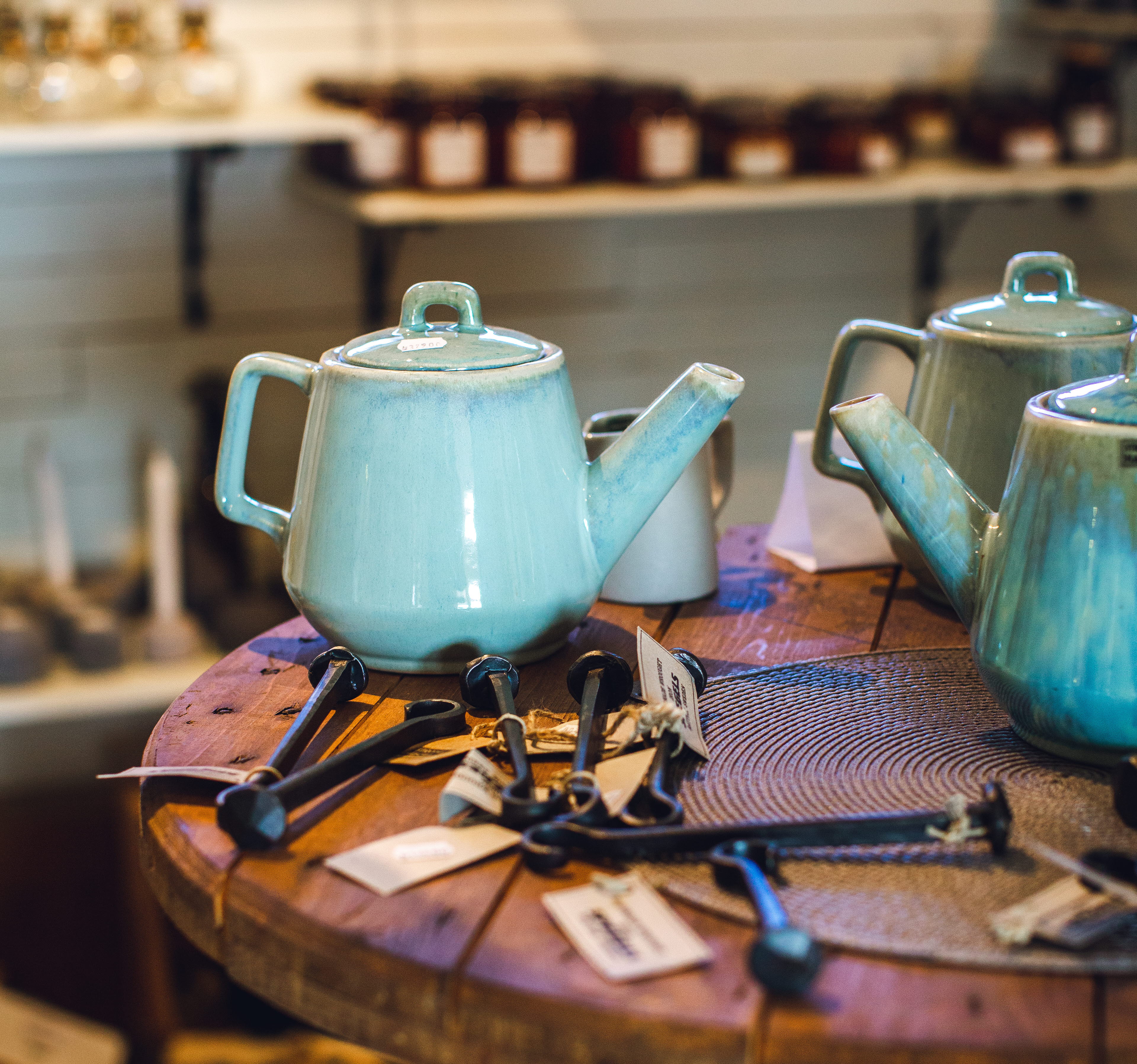 Några kaffekannor i turkost porslin på ett runt träbord.