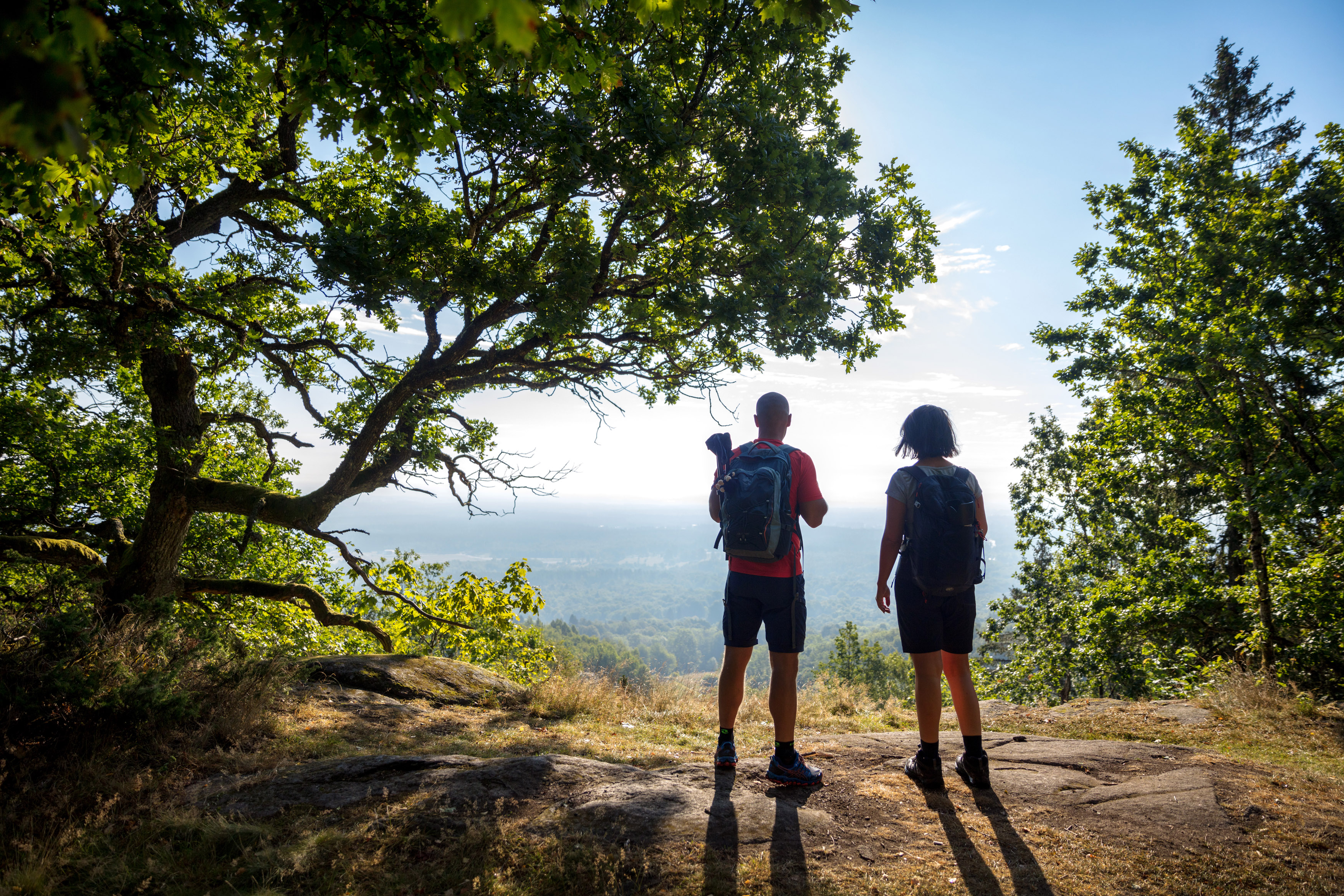 Två personer står på kanten av ett berg och blickar ut över ett storslaget landskap