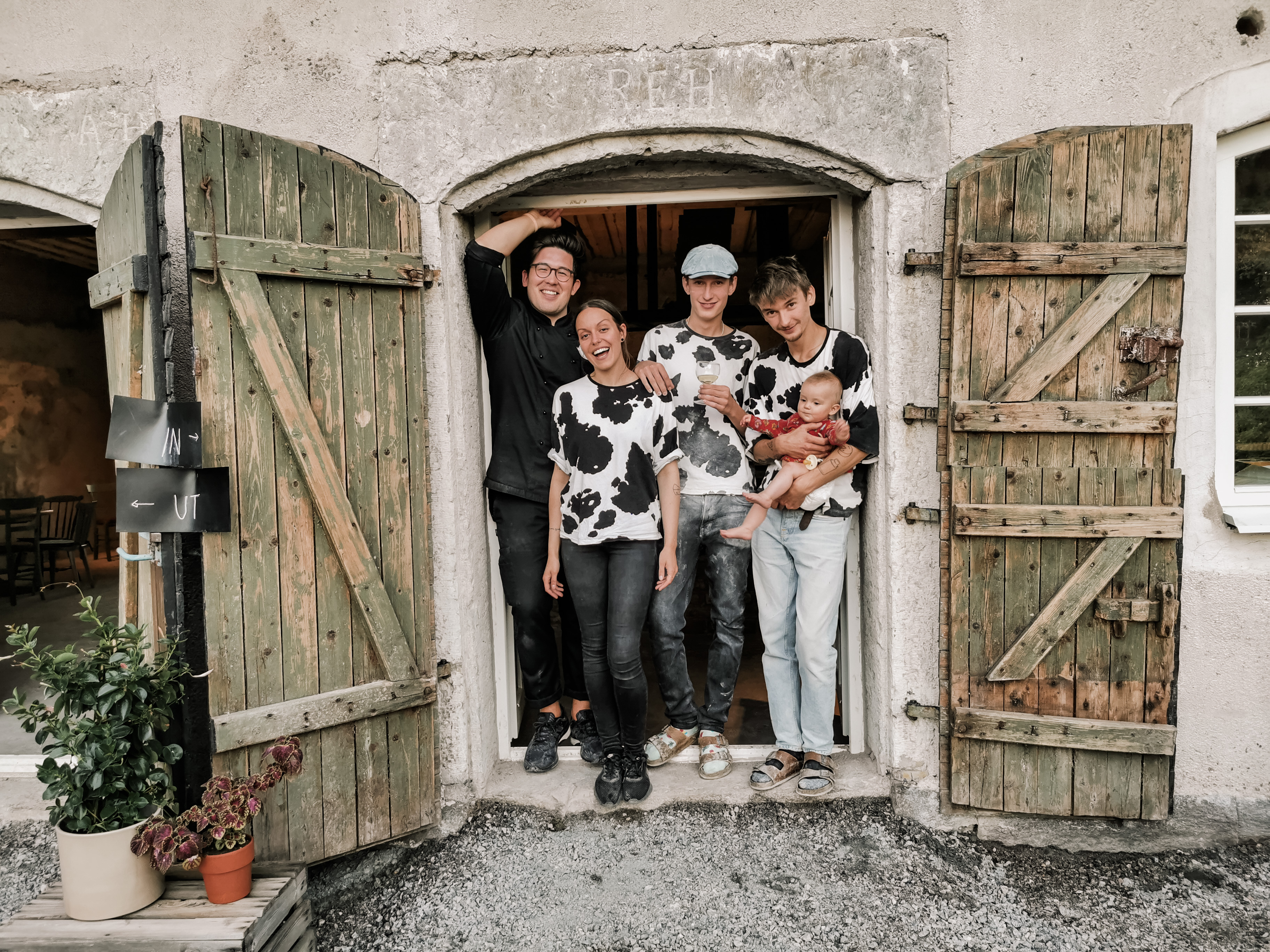 En kvinna och tre män står i en dörr. Den ena mannen håller en bebis.