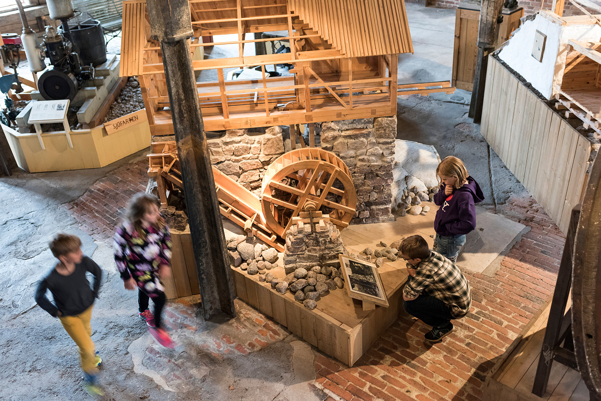 Bild tagen uppifrån på fyra barn som läser skyltar på stora modeller i trä.