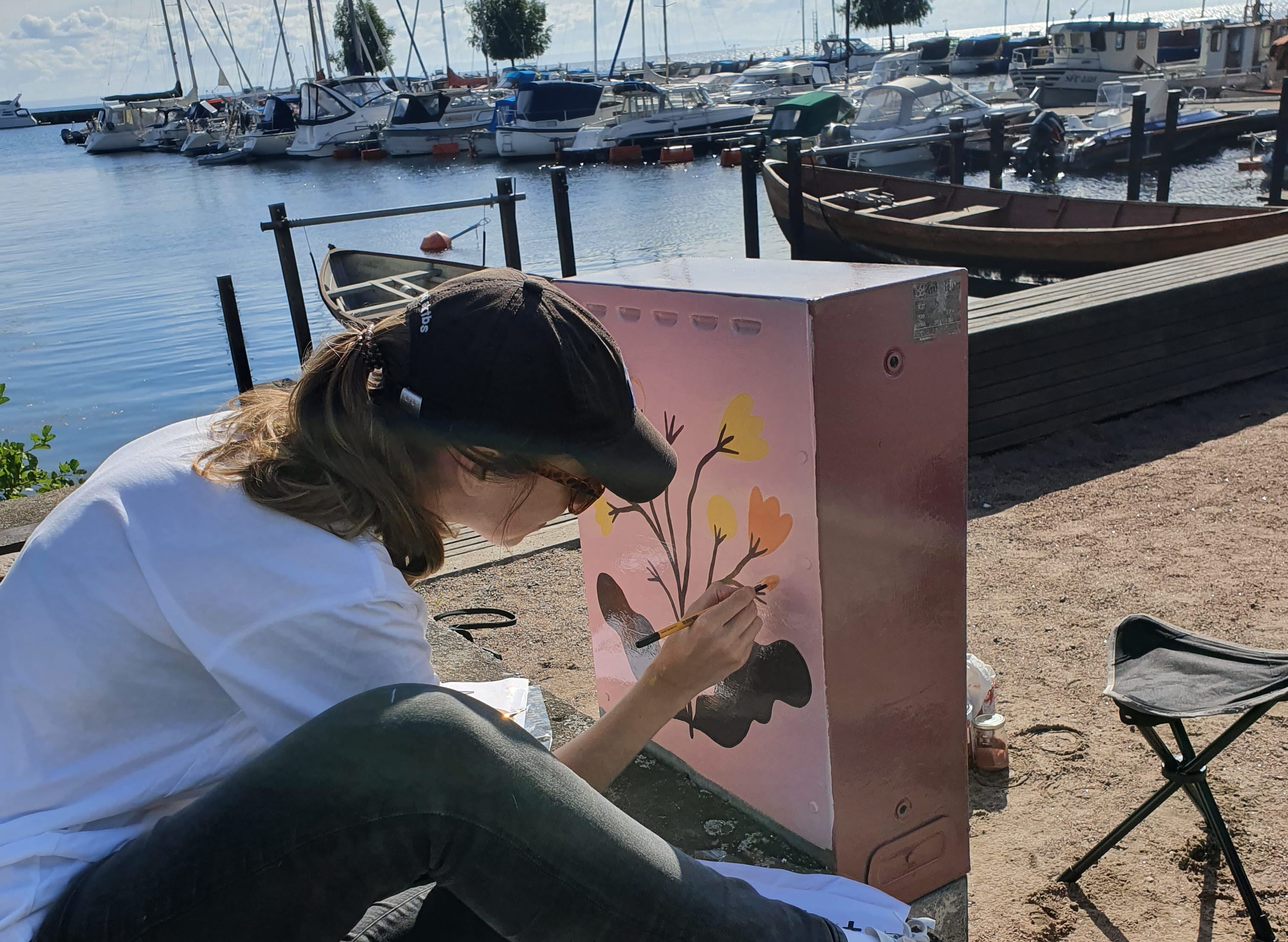 Kvinna målar elskåp i Hjo hamn