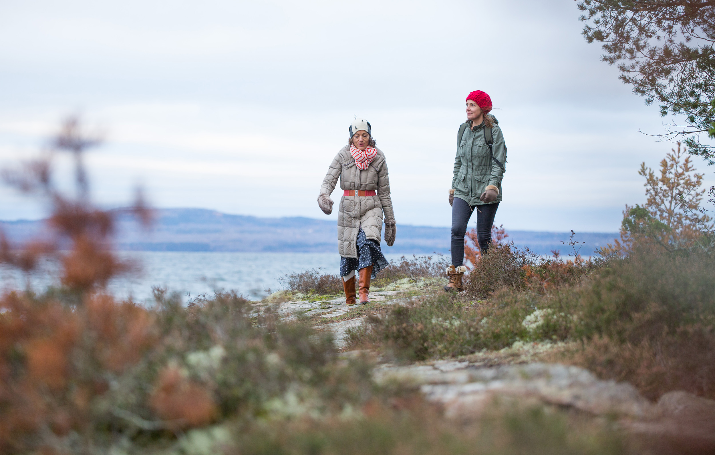 Two women hiking in the nature. Mountain Kinnekulle and lake Vänern are visible behind them.